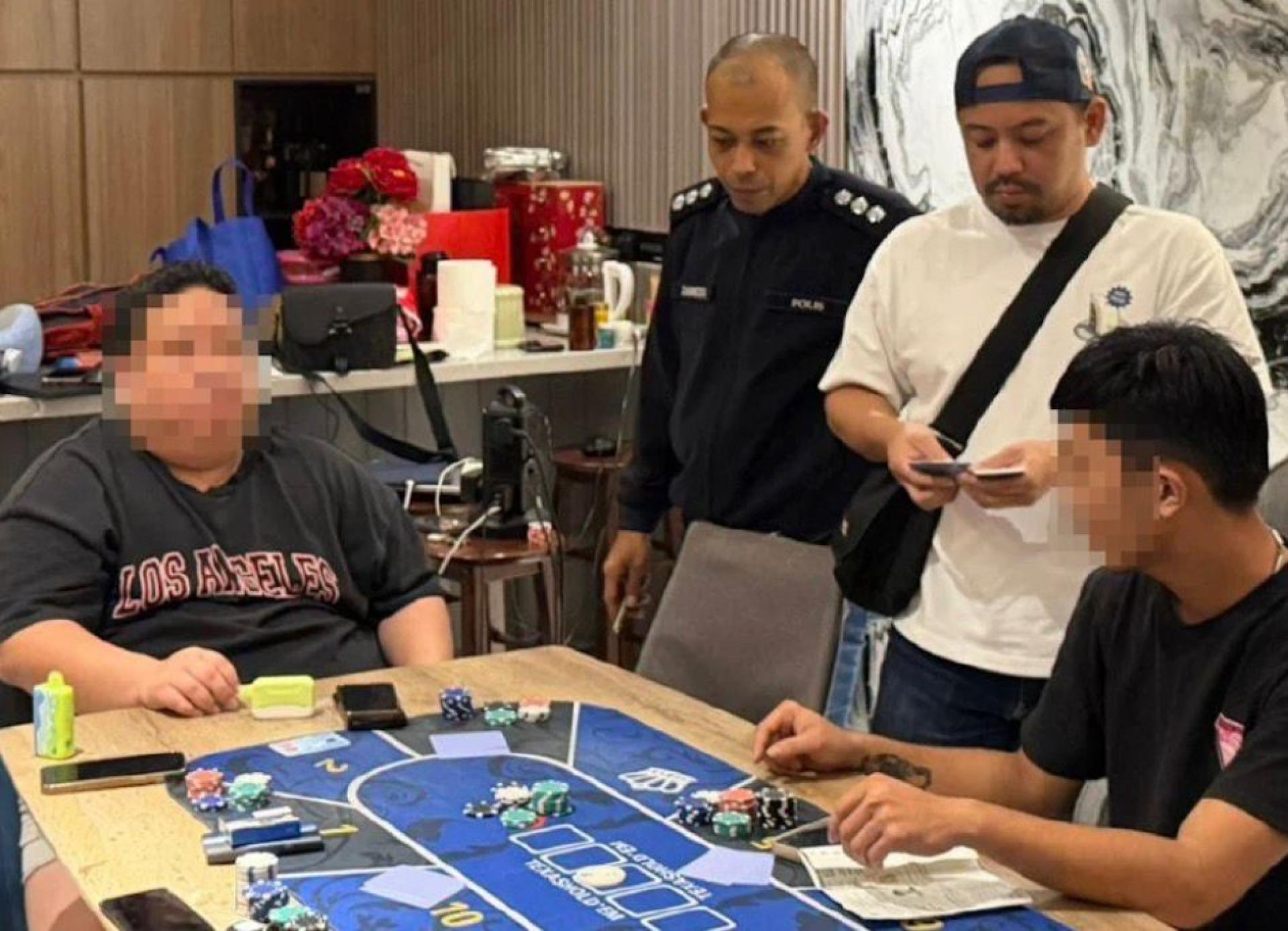 警方检查两名赌客的证件，他们落网前正在“迷你赌场”内进行扑克牌赌局。