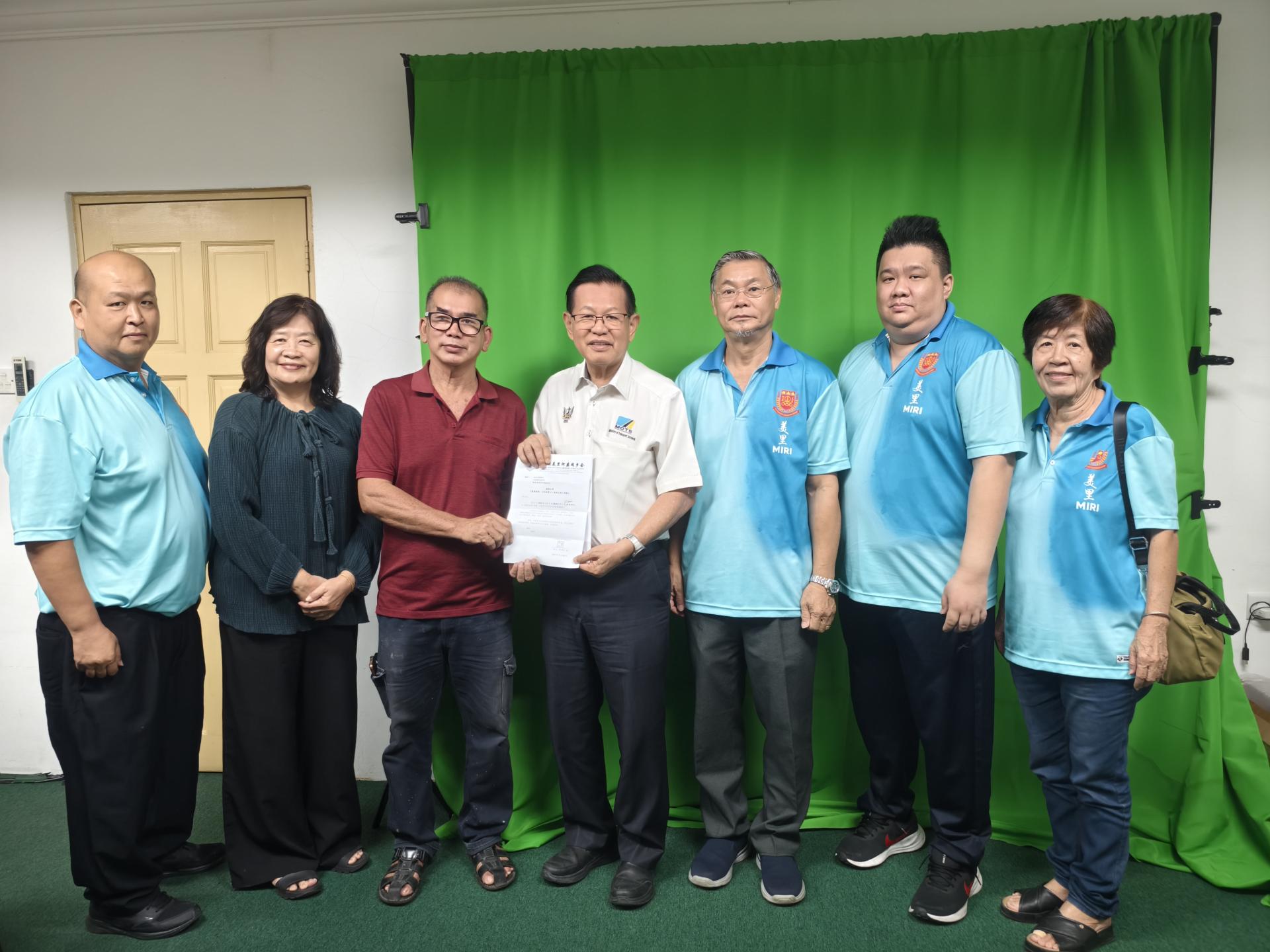 美里河婆同乡会教育主任兼《墨韵传情、文化献爱心》春联义卖筹备会主席邓展华（左3）移交邀请函予名誉顾问兼砂交通部长拿督斯里李景胜。左起为美里河婆同乡会青年团团长张鸿庆、财政李瑞香；右起为妇女组主任蔡素芳、青年团副团长黄义熙及及会长蔡传创。