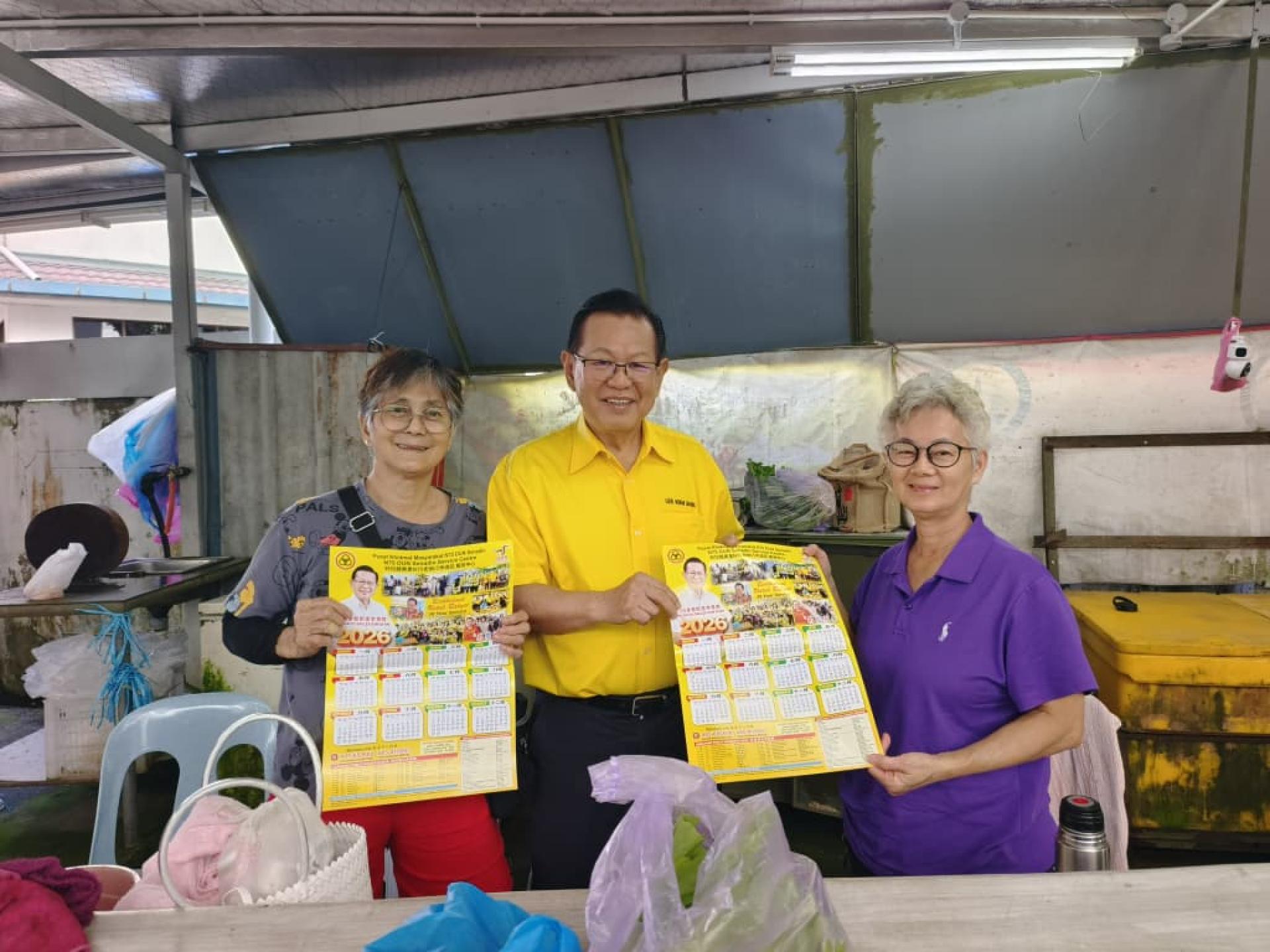 砂拉越交通部长兼史纳汀区州议员拿督斯里李景胜（中）派发史纳汀区州议员服务中心2026年月历，深受民众欢迎。