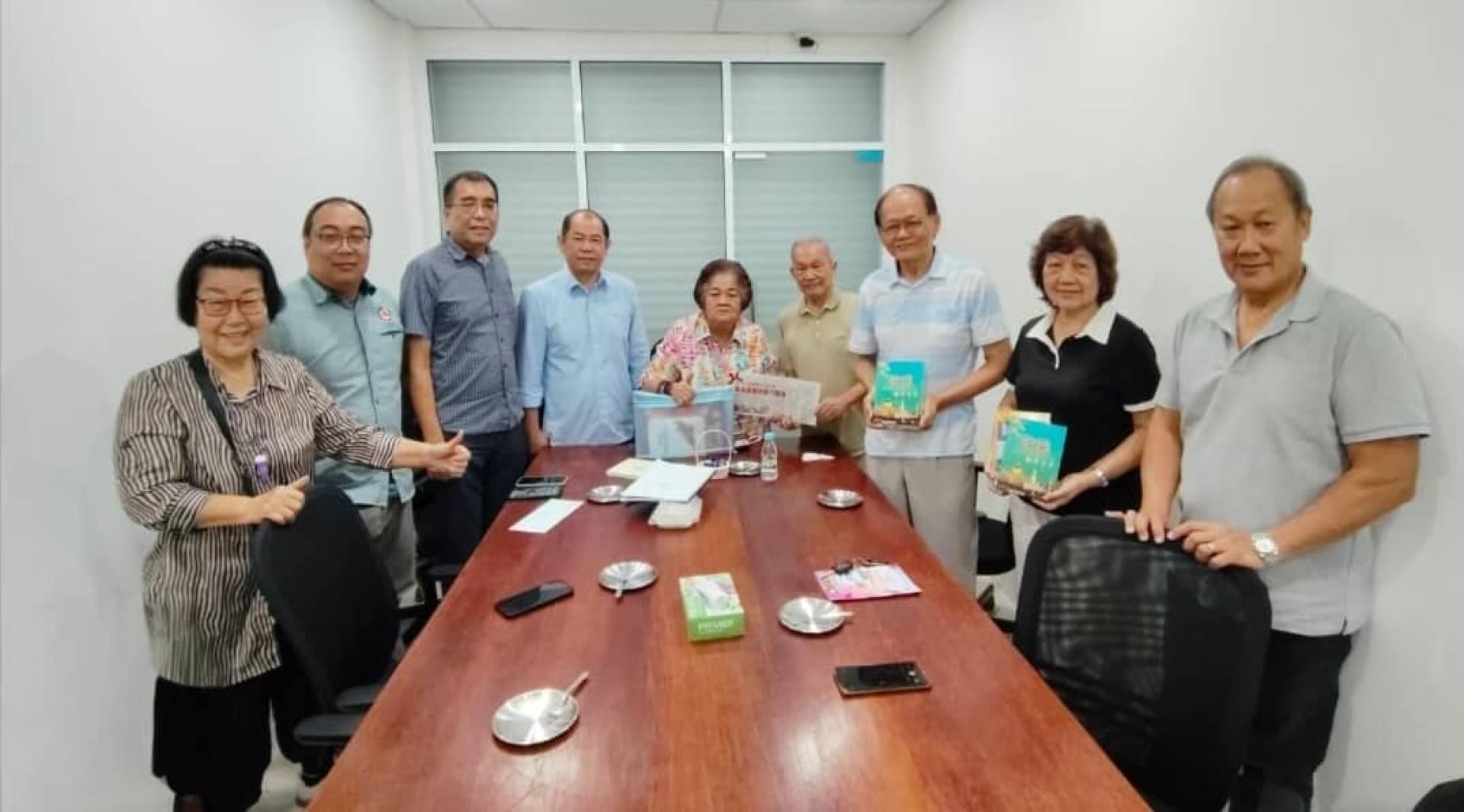 孙德安总会长赠书予温素华会长，并与与会嘉宾合影。