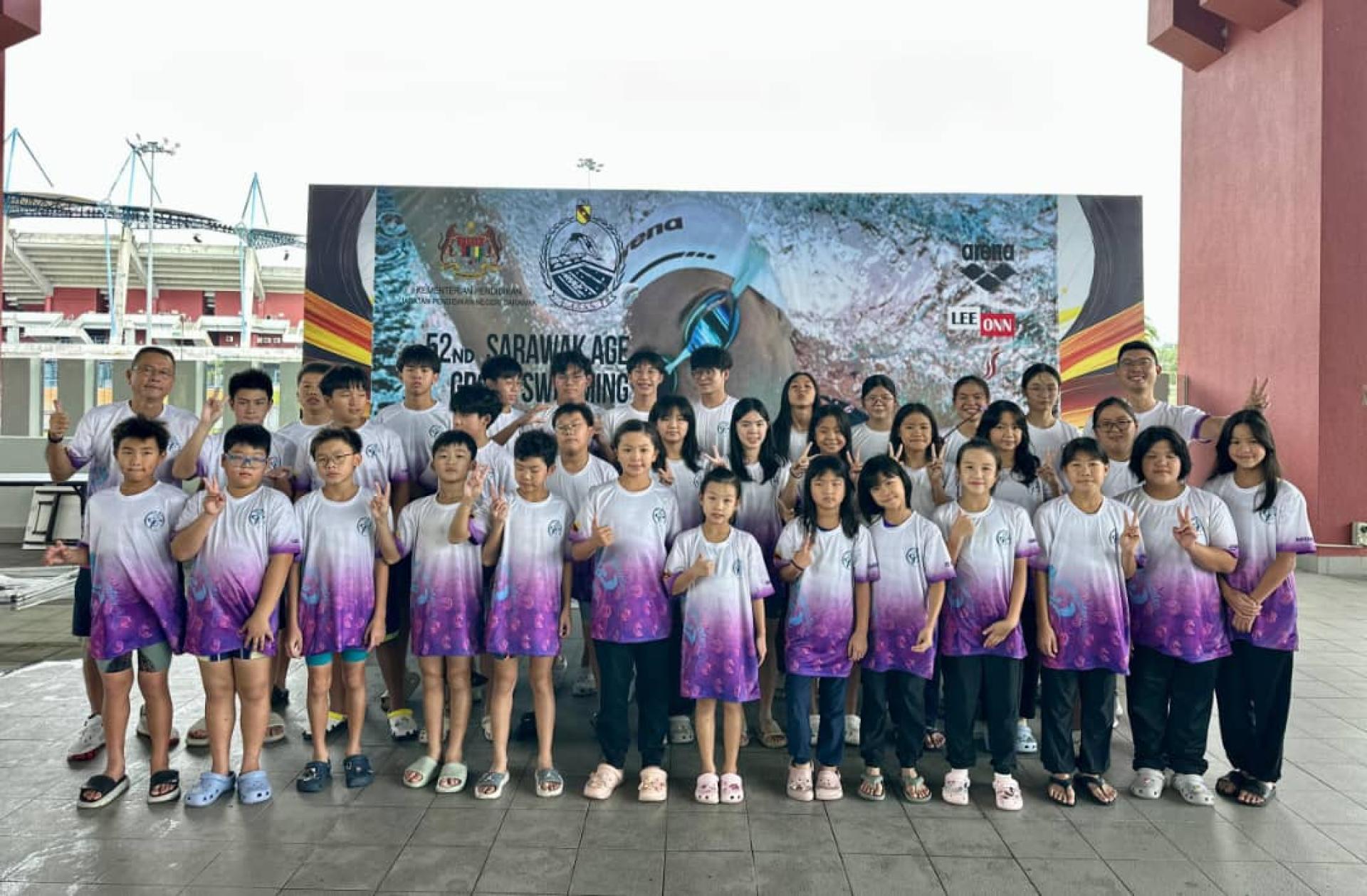 美里 Top Speed Aquatic 游泳俱乐部泳将与教练于2026年第52届砂拉越分龄邀请游泳锦标赛合  影。后排左为俱乐部顾问兼教练钟易强，右为俱乐部主席兼教练钟秉哲。