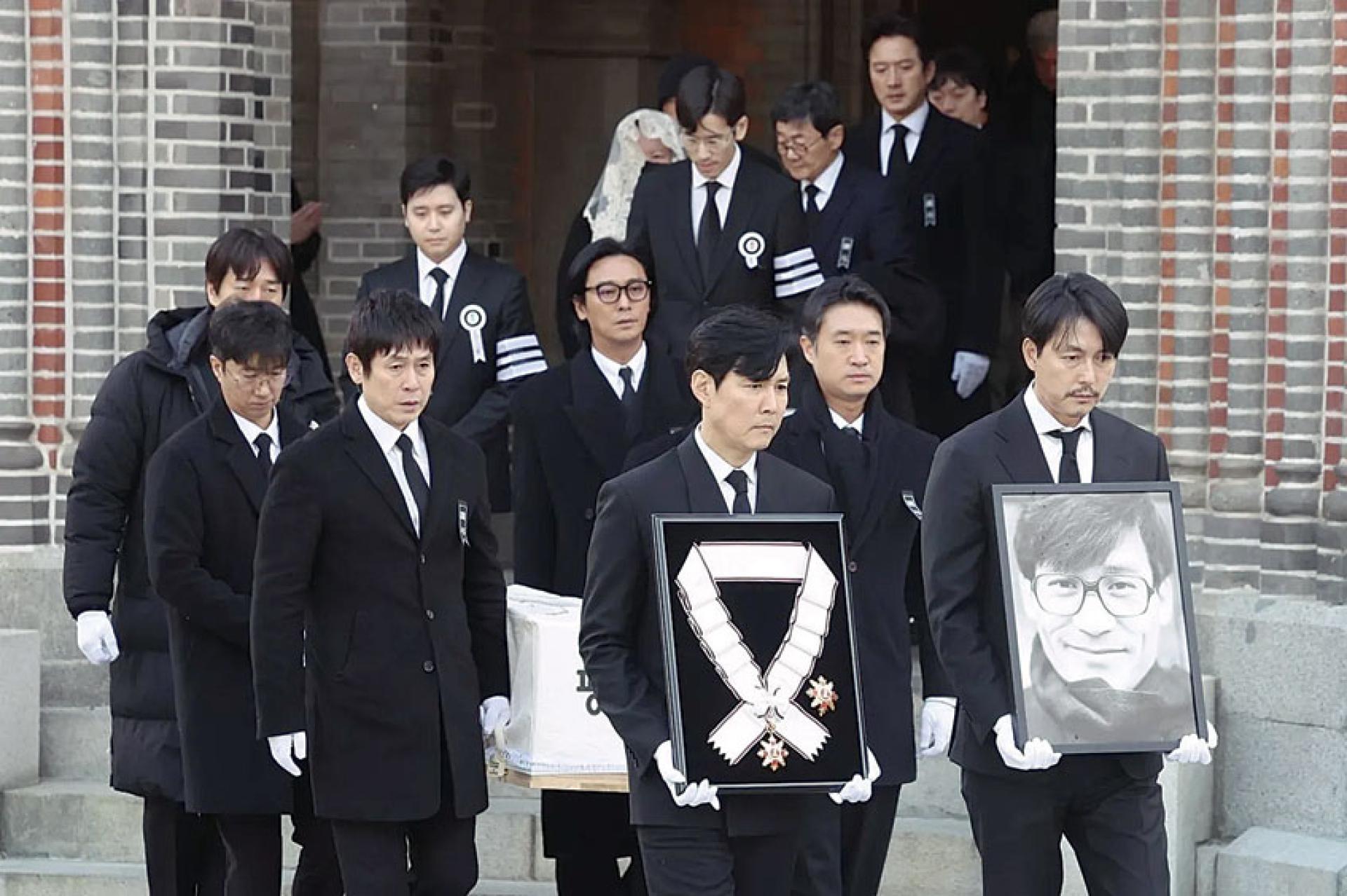 郑雨盛（右）与李政宰捧着安圣基的遗照及勋章，影坛后辈都跟在后侧送行。