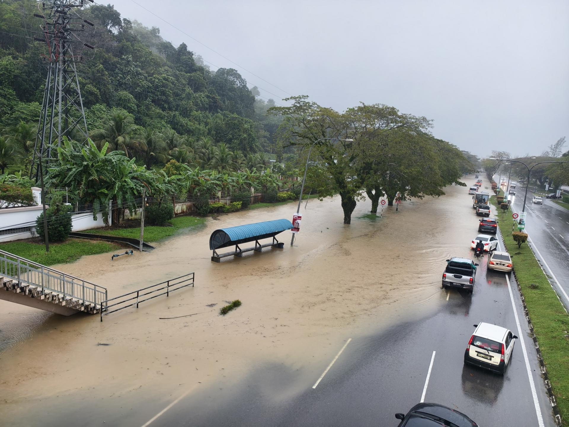 富丽华人行天桥前方美里埔奕路今午12时道路沟水外溢，路面积水严重，车辆通行受阻。