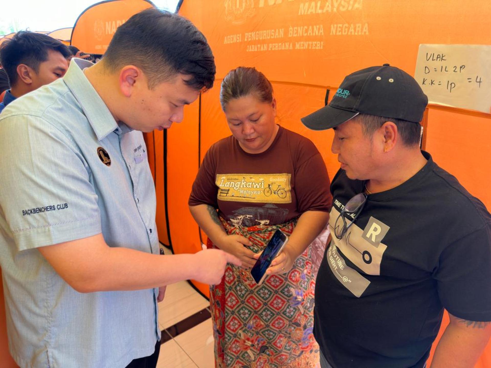 赵俊文（左）向受水灾影响的灾民了解情况。