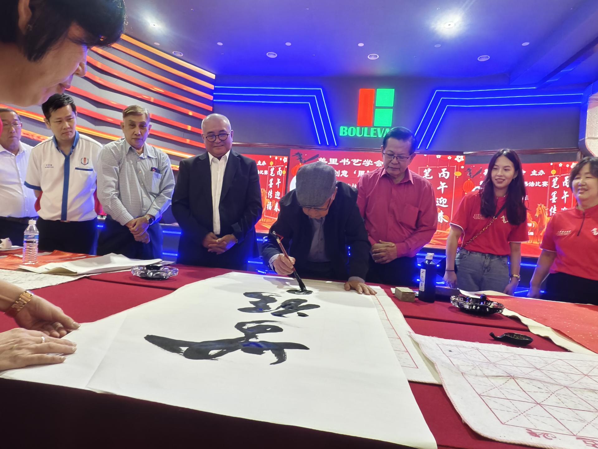 美里书艺学会名誉会长陈乃豪现场挥毫。右起为美里书艺学会会长甘美美、筹备会主席温思捷、主宾兼砂拉越交通部长拿督斯里李景胜、市长俞小珊，以及美里华总会长许信隆（左2）等。