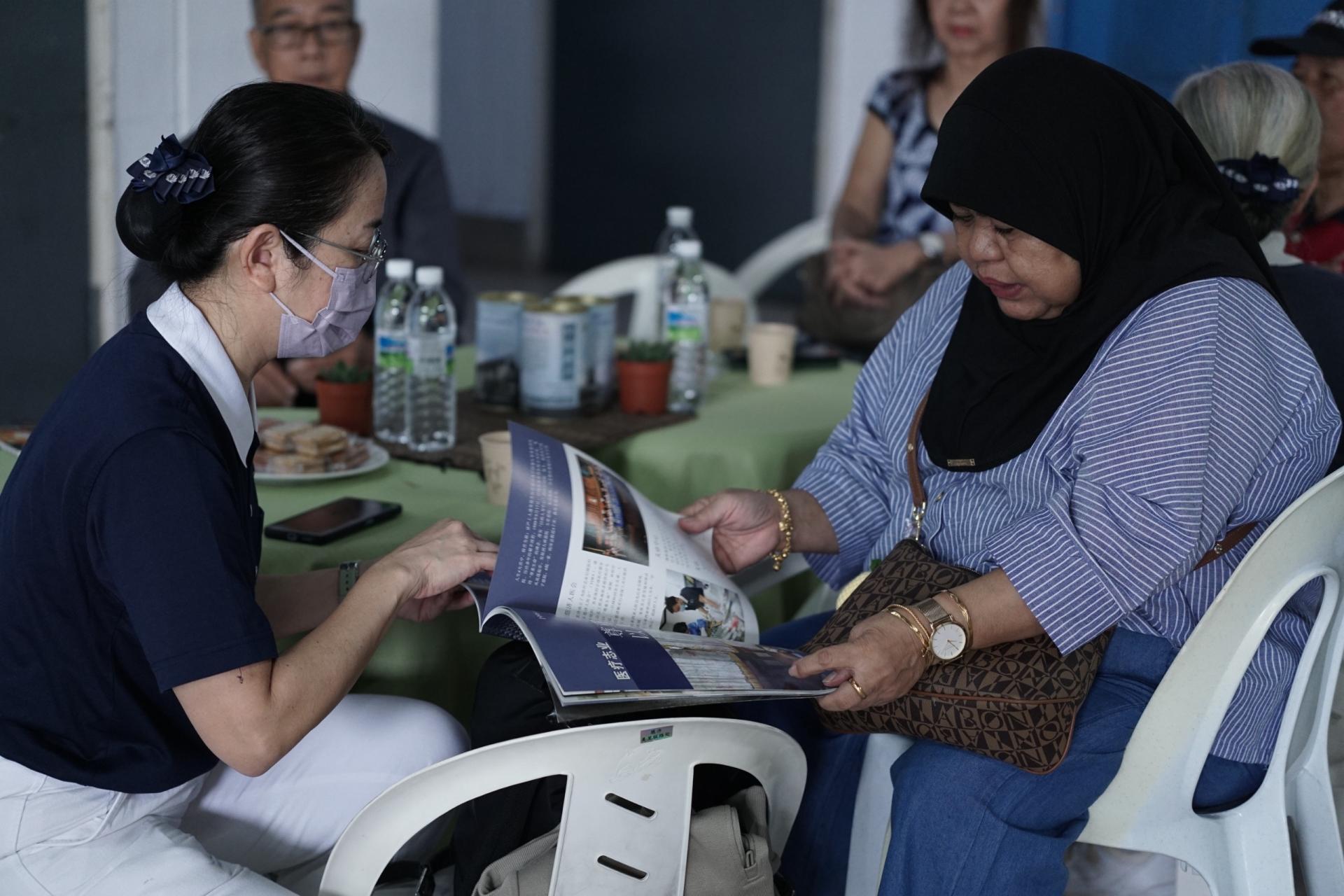 美里慈济志工锺明瑂（左）在义诊会场爱洒活动中，向巫裔病患介绍慈济人文精神。