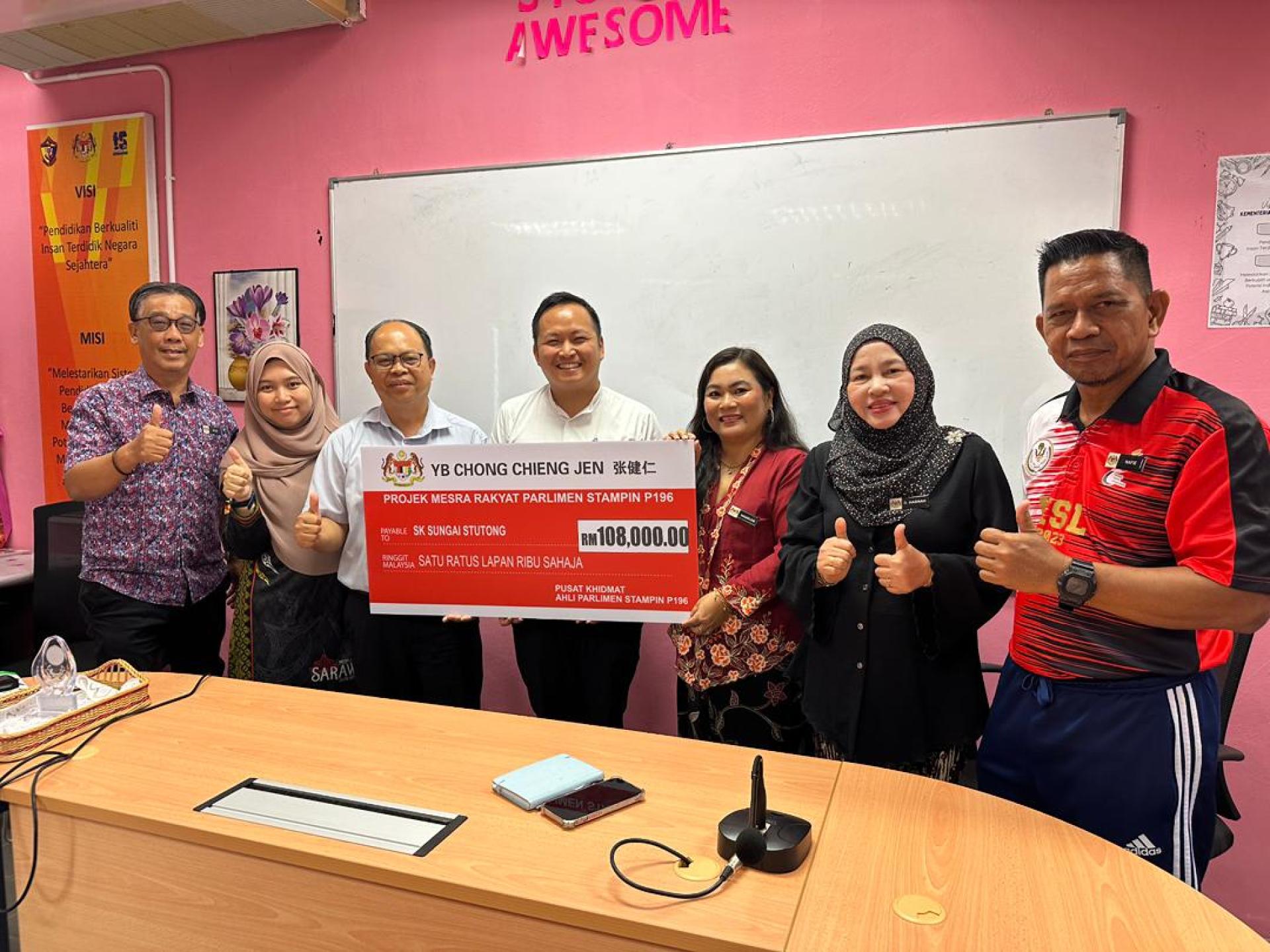 江峰年（中）代表移交捐款给双溪实都东国小。