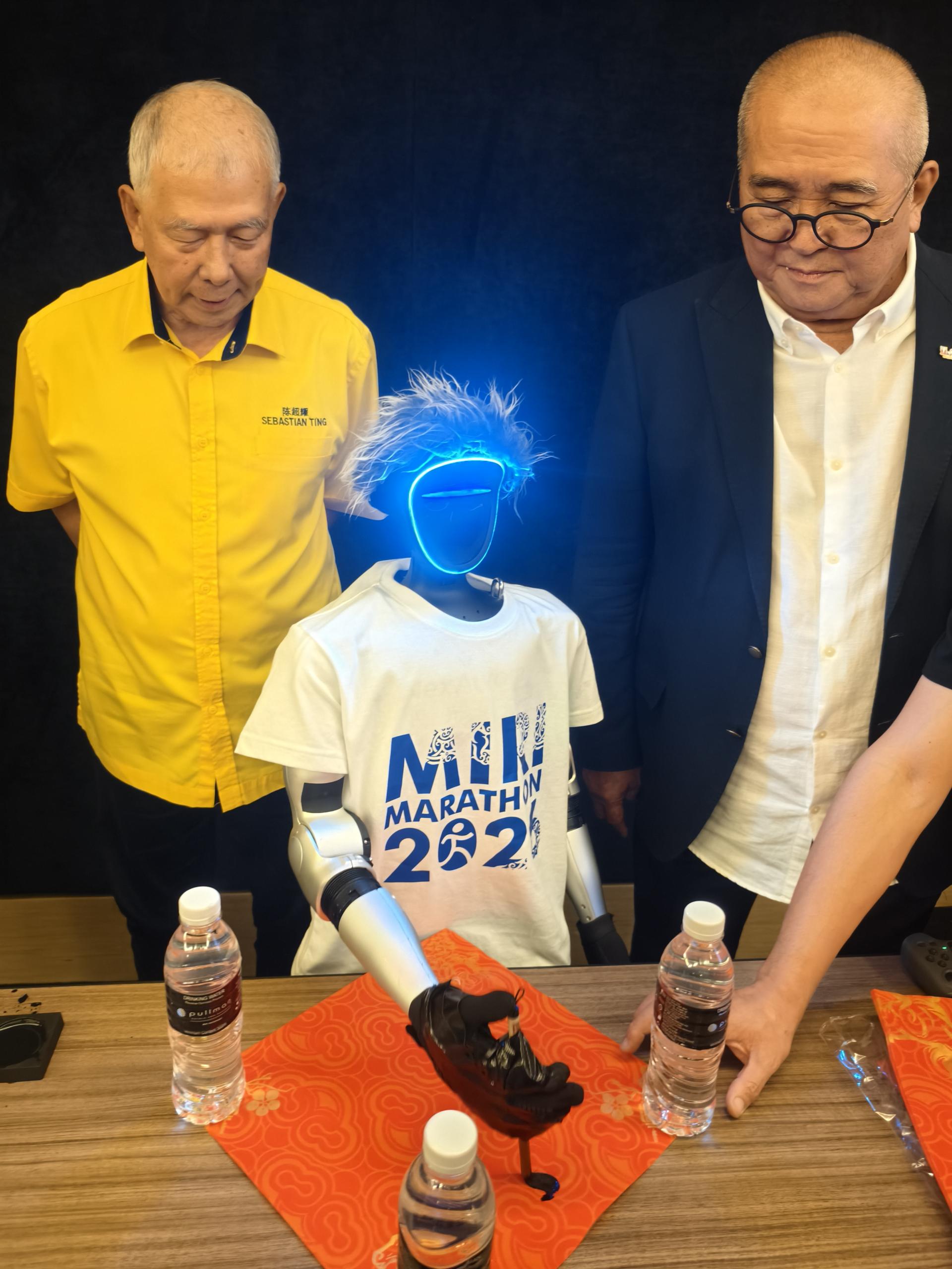 拿督陈超耀（左）观看人形机器人现场挥毫书写“福”字，感受科技融入文化的创意魅力。右为美里市长俞小珊。