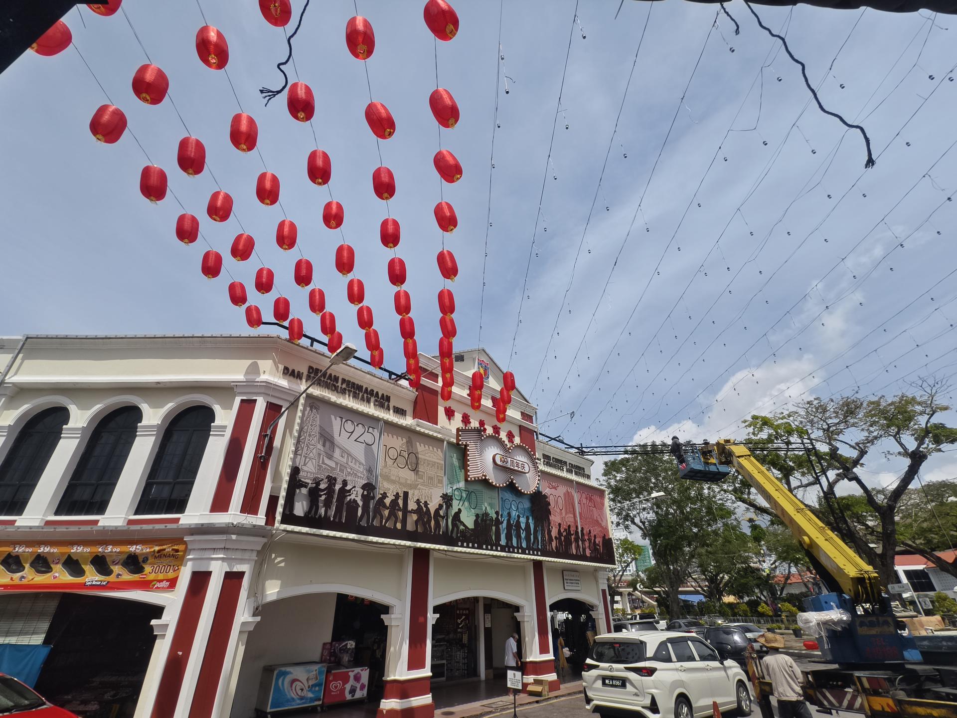 美里中华总商会大楼展开新春布置工程，工作人员高空作业悬挂红灯笼，为迎接马年新春营造浓厚节庆氛围。