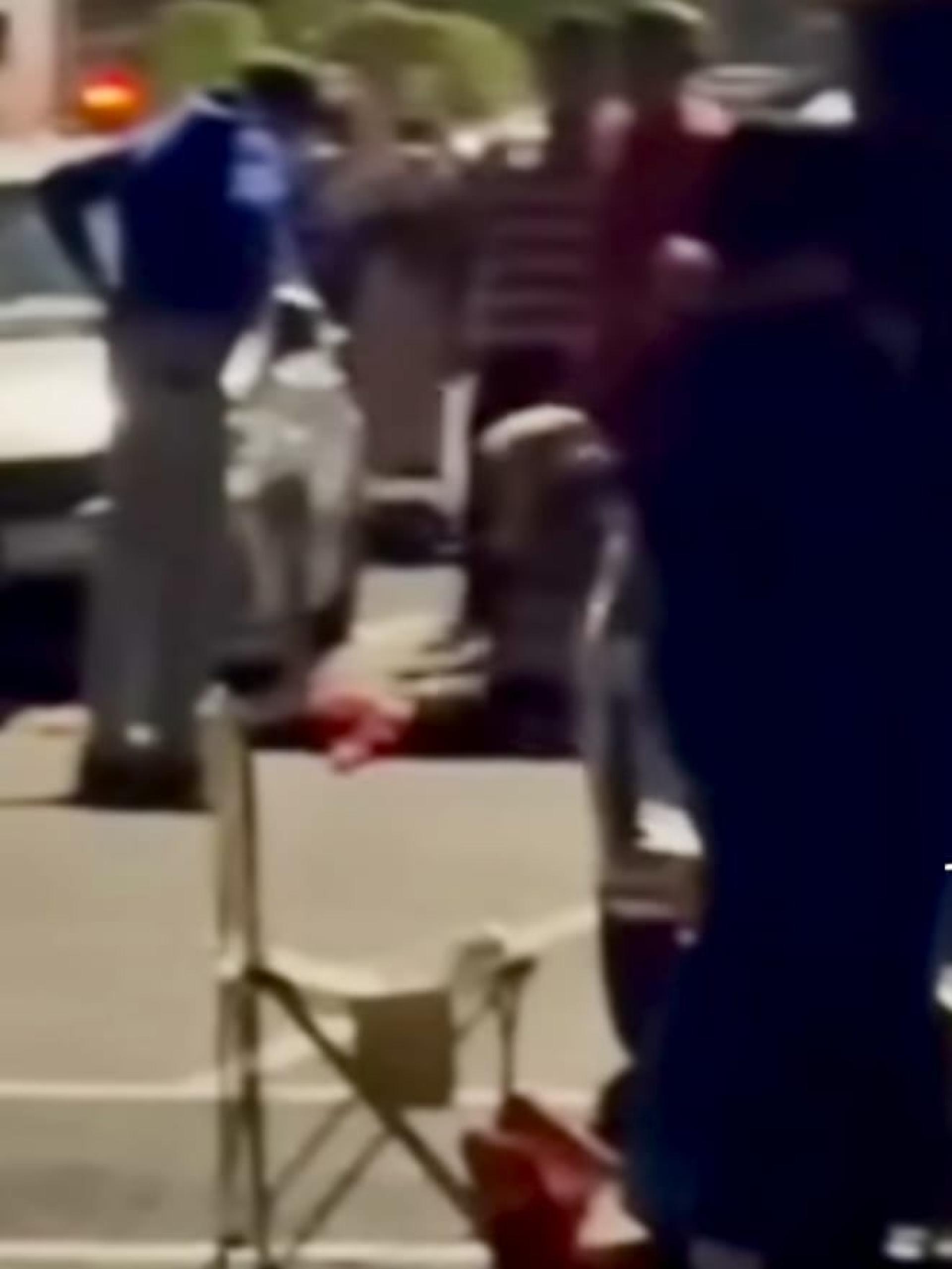 一名女子摇晃着一名倒卧在地的孩童，现场传来哭喊声。