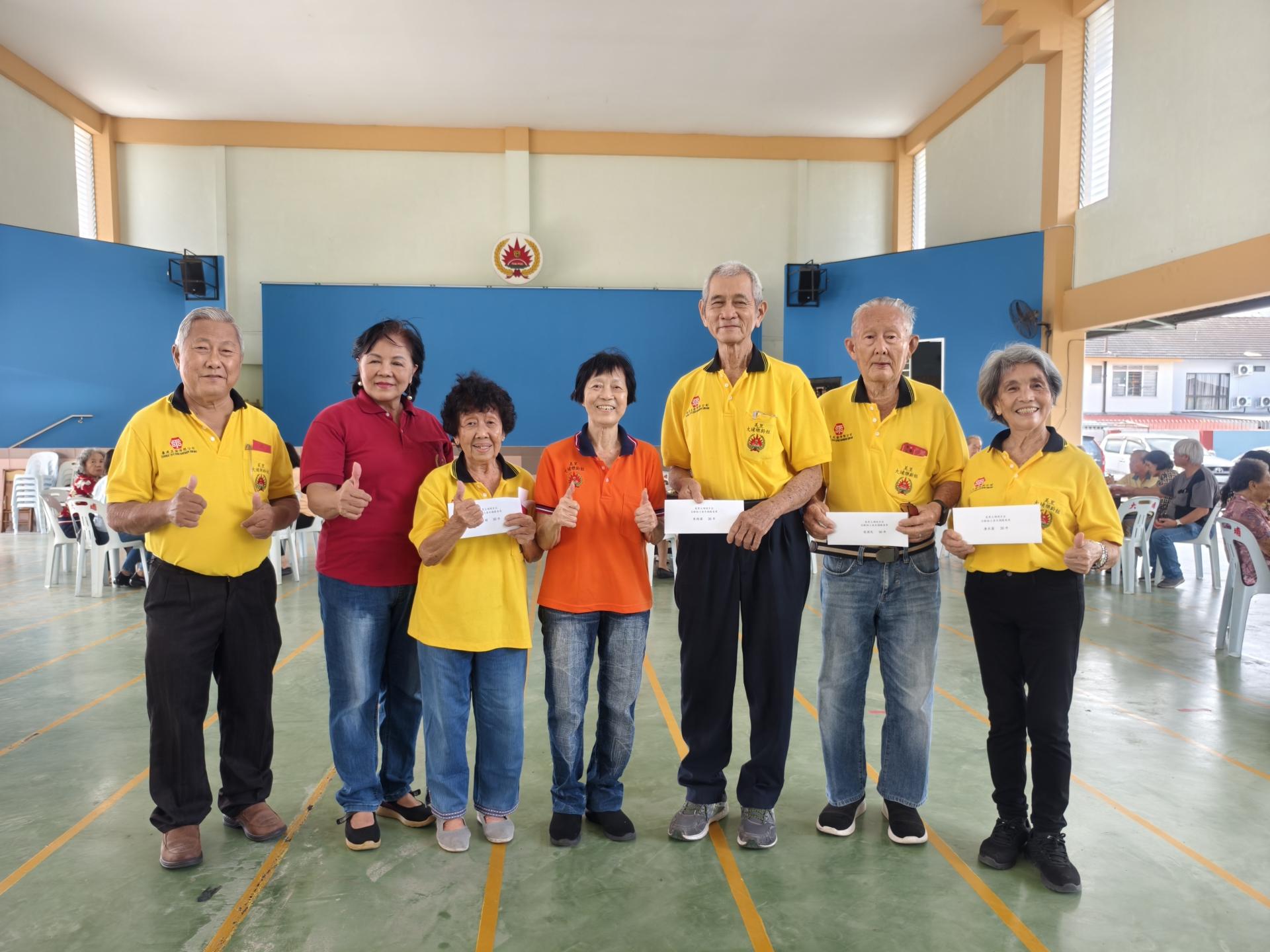 美里大埔同乡会乐龄组主任罗玉莲（中）颁发乐龄组长期服务奖表扬4位服务超过30年的工委，分别为朱维谋（右3）、连国民（右2）、唐水菊（右1）及陈素娟（左3）合影。左起为杨贤曾及甲必丹陈彩萍。