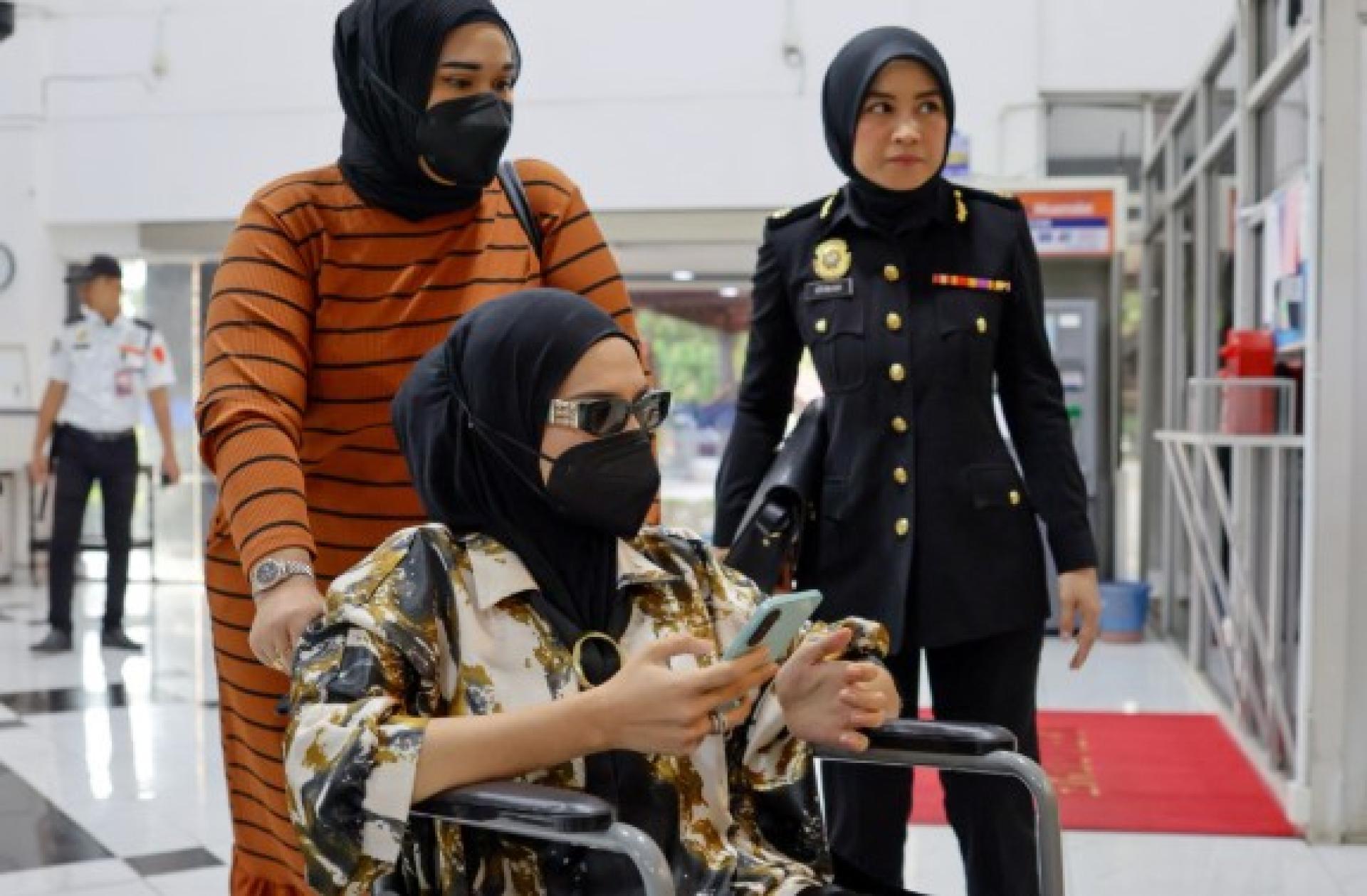 莎瓦妮乘坐轮椅进入法庭大楼，面对去年收受5000令吉非法活动收益的罪控。