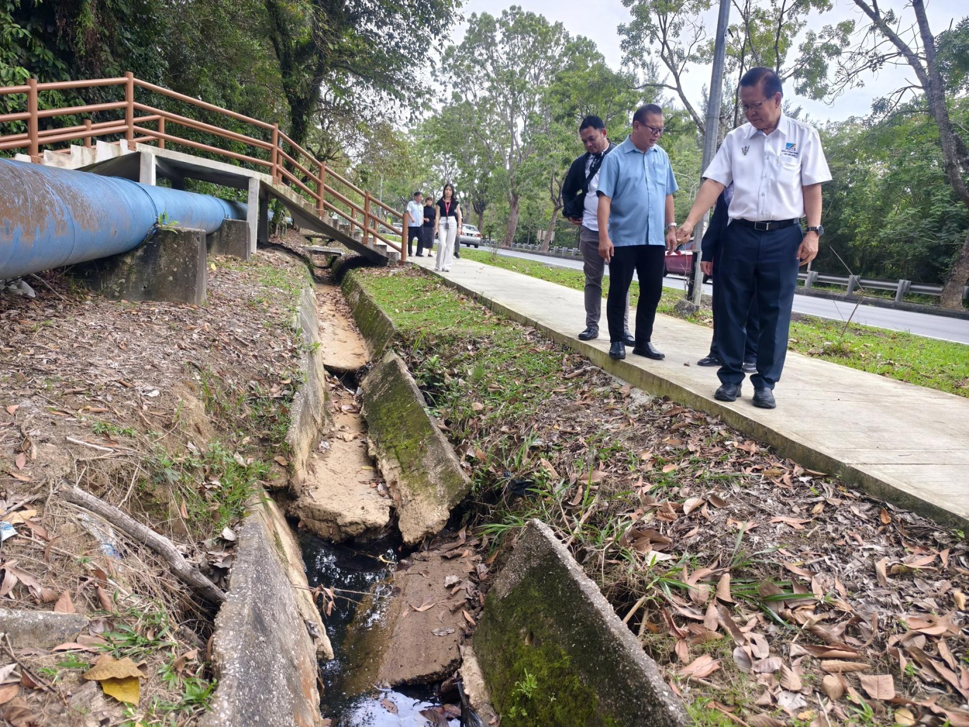 拿督斯里李景胜（右）今早前往美里公共公园岩石悬崖公园巡视当地因长期侵蚀导致排水沟及桥涵结构坍塌的问题。
