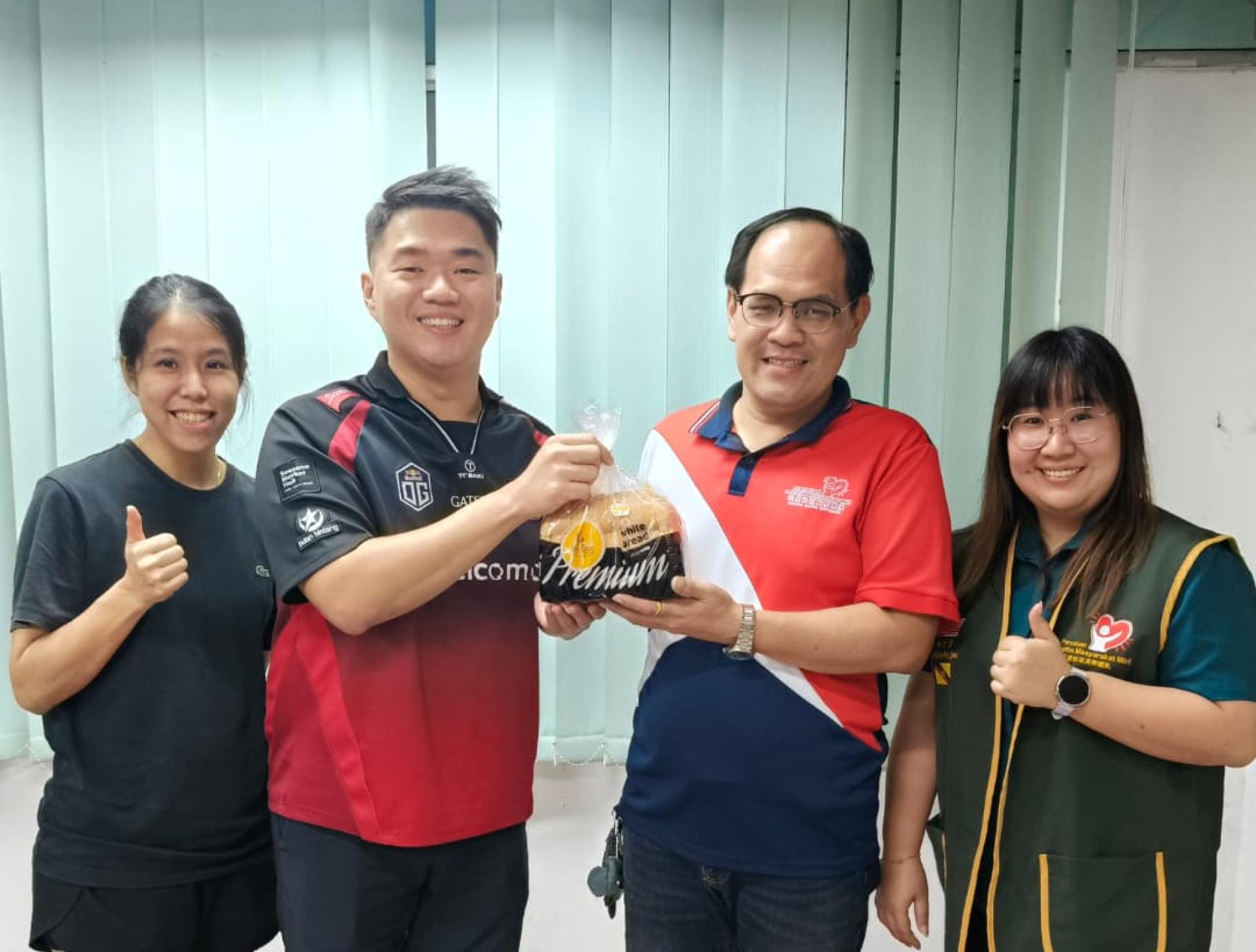 美里双胞胎烘焙坊创办人李俊达（左2）移交赞助品予美里社区关怀团队副会长兼联合筹备会主席杨万勇；左为财政谢凯玲，右为公关丘紫霞。