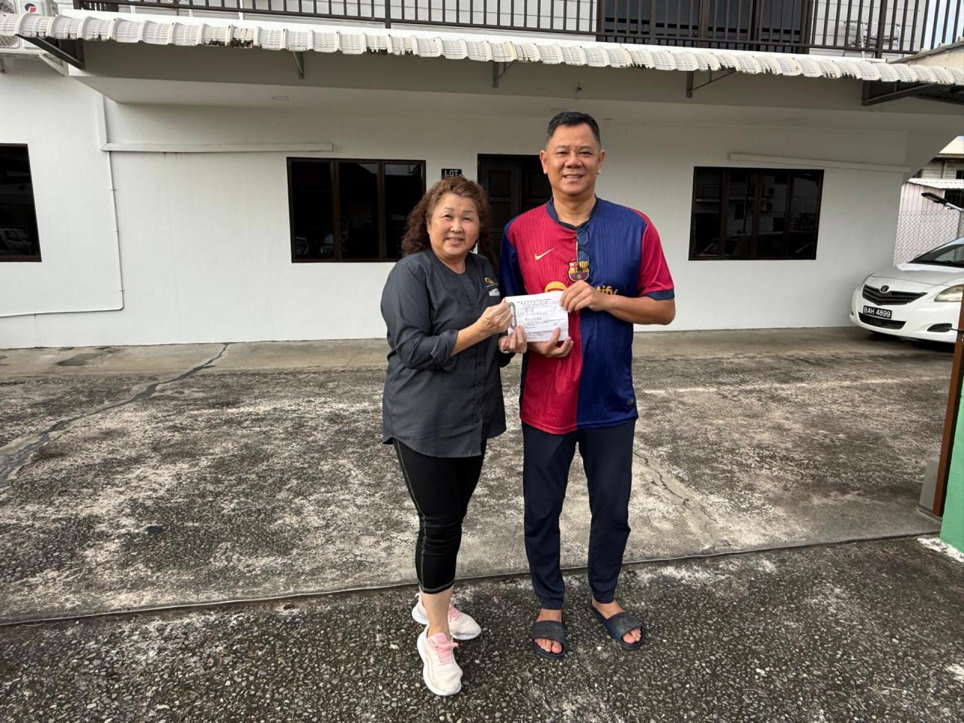 沈秋香（左）将收据移交予黄汉来