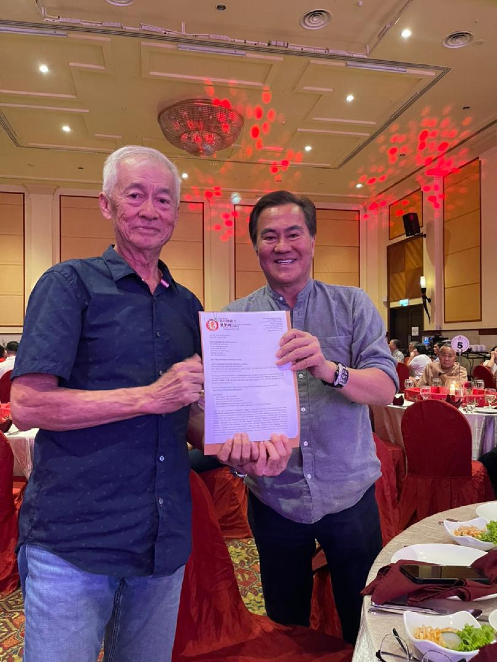 砂拉越华人公会永久名誉顾问拿督许庆璋（右）移交“2026福马迎春联欢晚会”邀请函予拿督黄国惠。