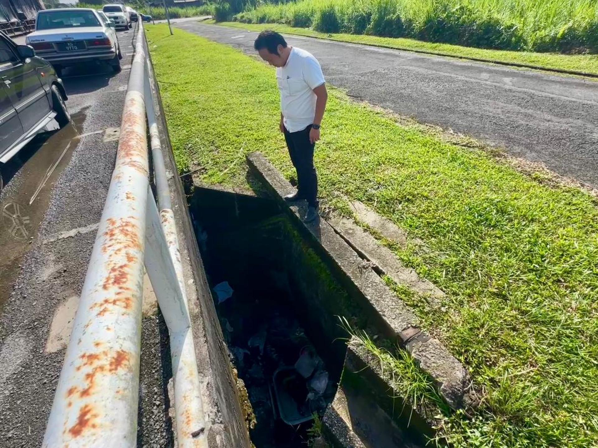 江峰年视察堆积大量垃圾的沟渠。