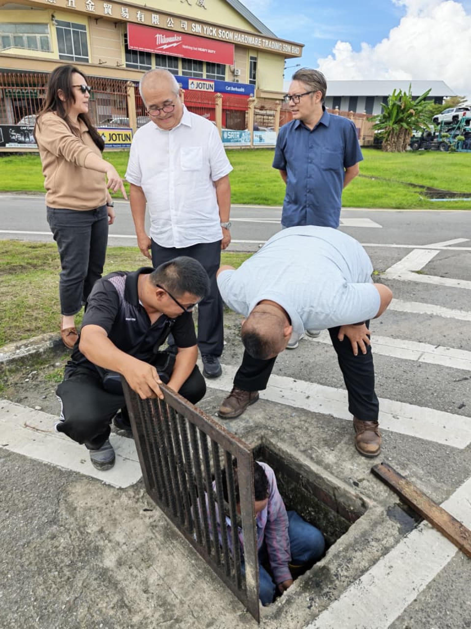俞小珊（中）带领市政局官员巡视珠巴沿河排水沟，了解淤塞及出水口被植被覆盖情况。