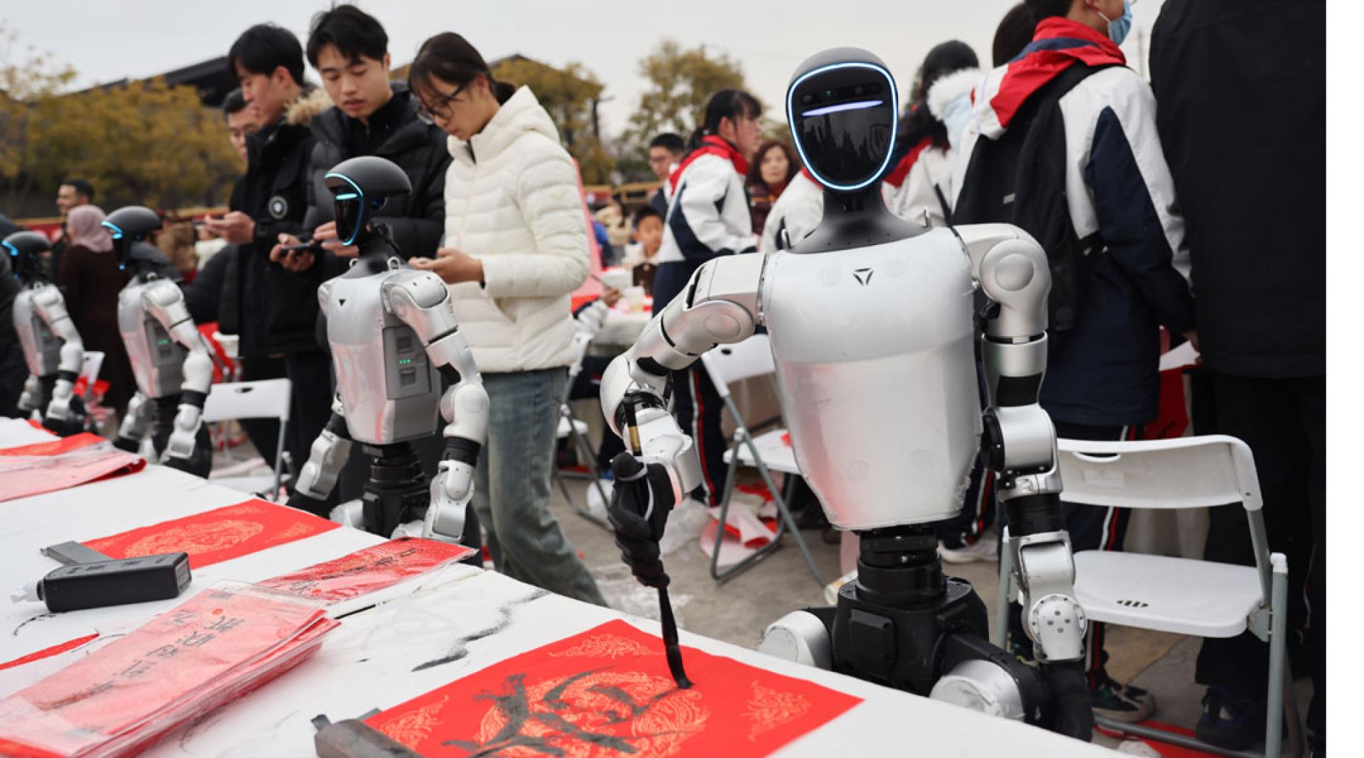 4台人形机器人“灵巧”地握持毛笔，与书法家同台展开了一场别开生面的“书写竞技”。（图：中新社）