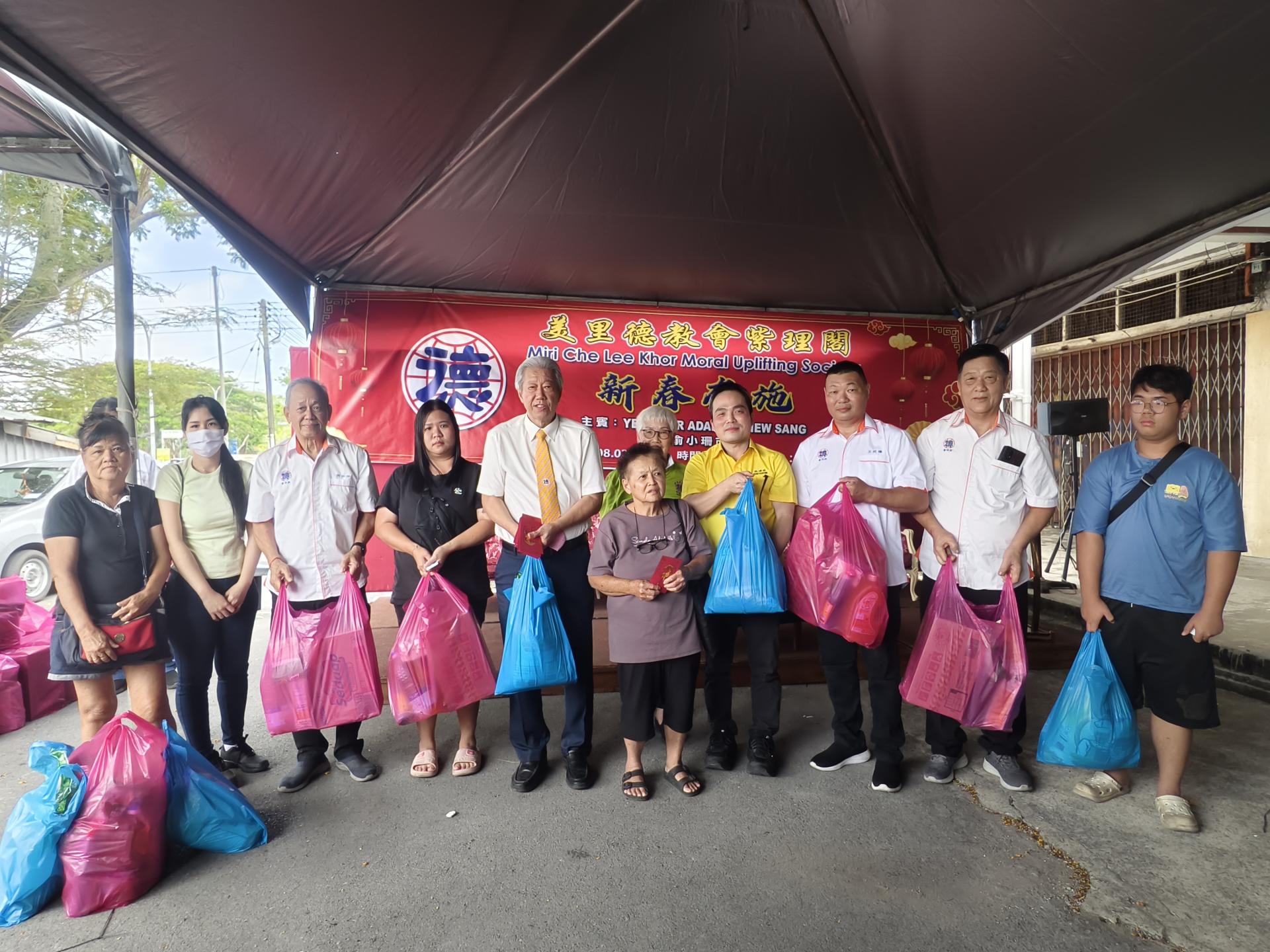 美里德教会紫理阁举办一年一度的新春布施活动，主宾美里市长兼埔奕区州议员俞小珊的代表张嵻洺（右4）、紫理阁阁长贝清湛（左5）、署理阁长何洪坤（左3）、副阁长杨裔富（右2）及筹备会主席王武德（右3）移交新年礼品与红包予受惠者。