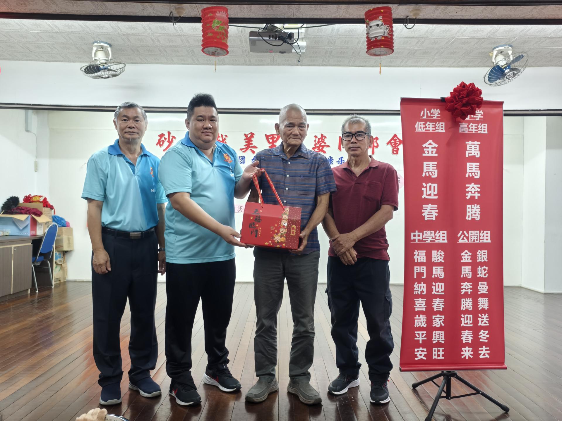 筹备会主席黄义熙（左2）赠送纪念品给主宾砂拉越交通部长拿督斯里李景胜，由其代表天猛公杨惠生接领。左为美里河婆同乡会会长蔡传创，右为文化教育基金组主任邓展华。