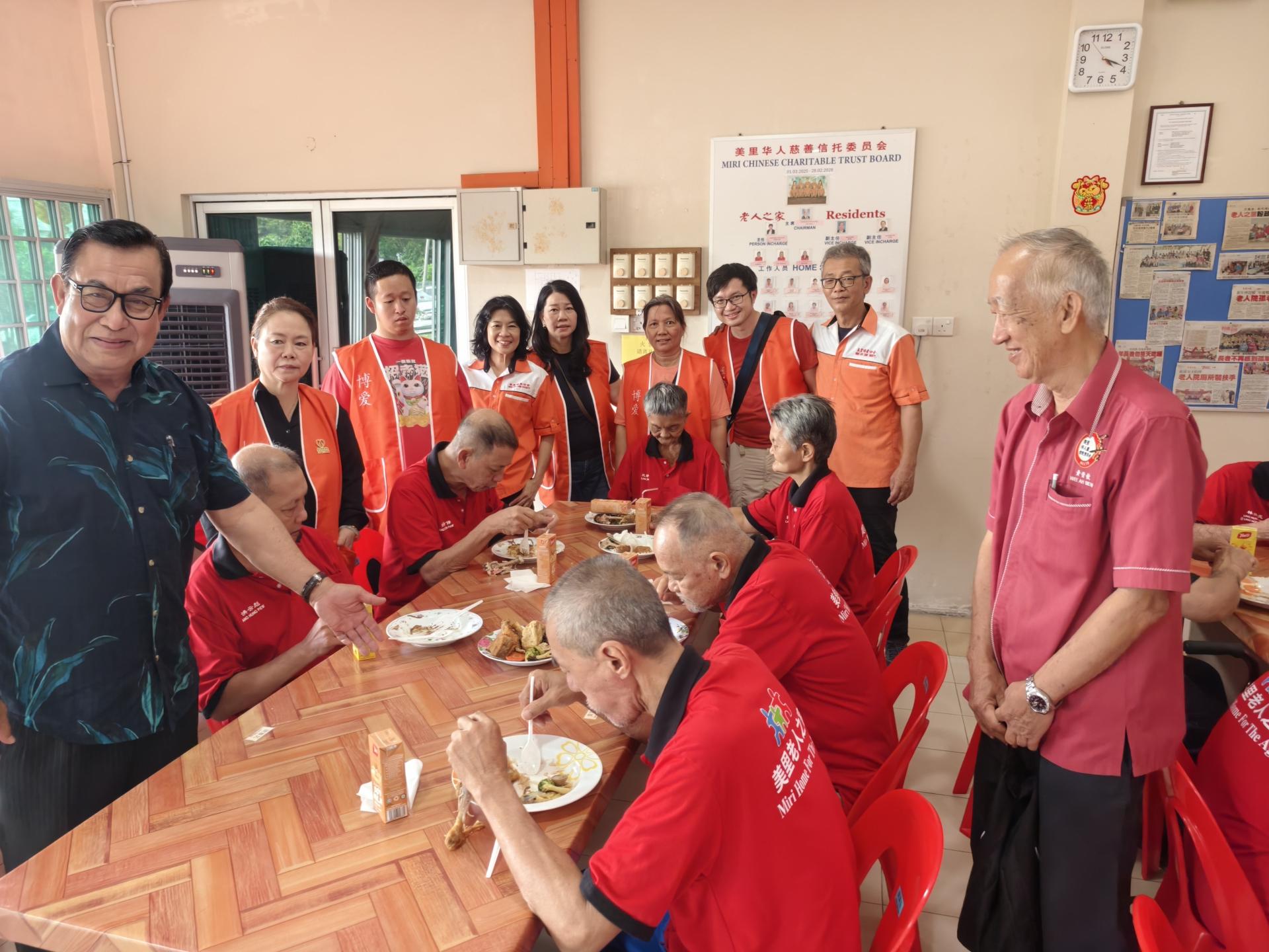 主宾李景胜的代表本固鲁蔡刚明（左）与美里博爱协会成员一同向老人端上美味佳肴。