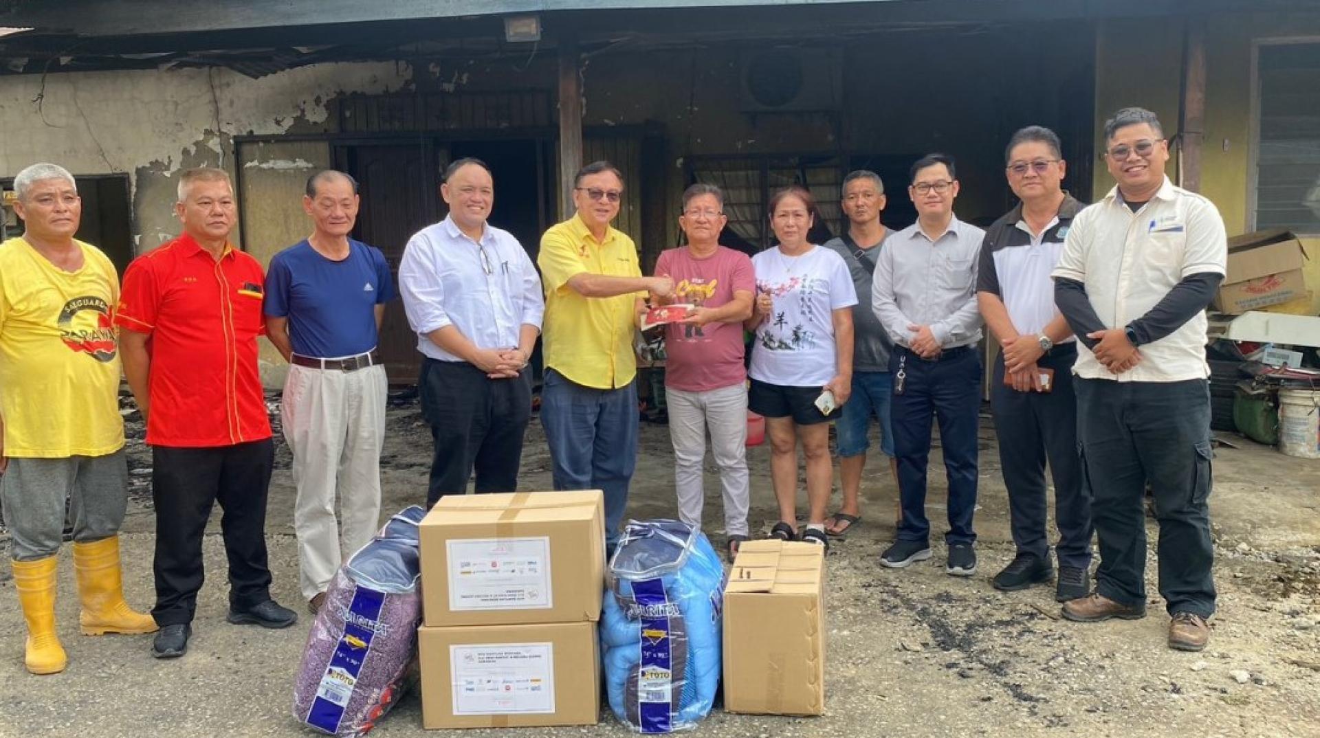 罗克强（左5）在火灾现场向沈天福提供援助。