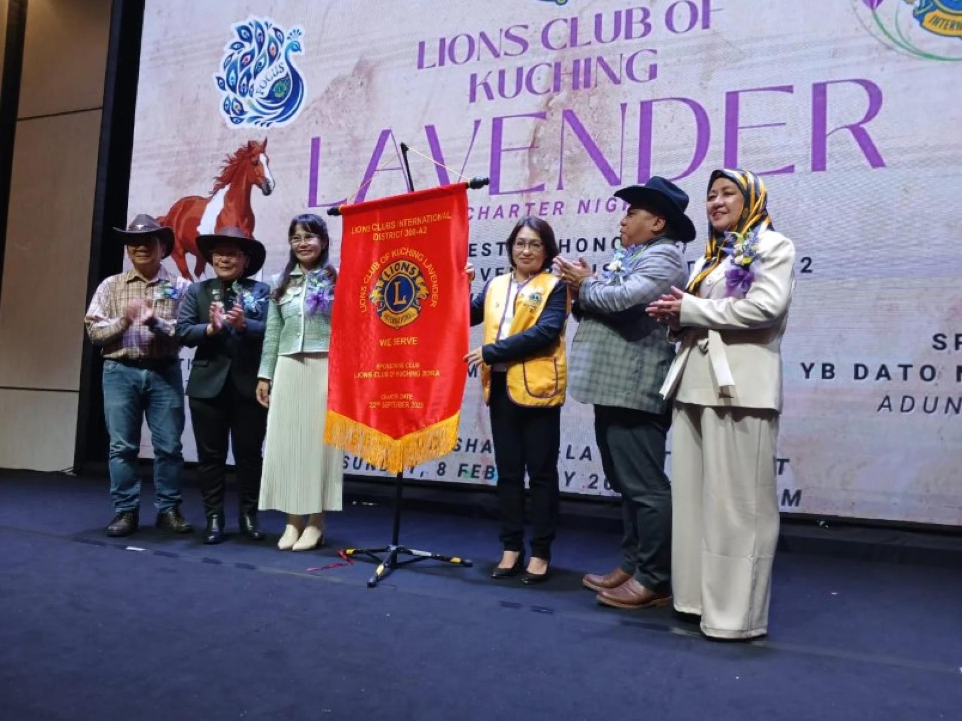 Connie Tan（右3）与其他嘉宾（从左至右：Sim、前会长Christopher Kiyui博士、Lee、Miro及Ellis Suriyati）共同展示古晋薰衣草狮子会旗帜。