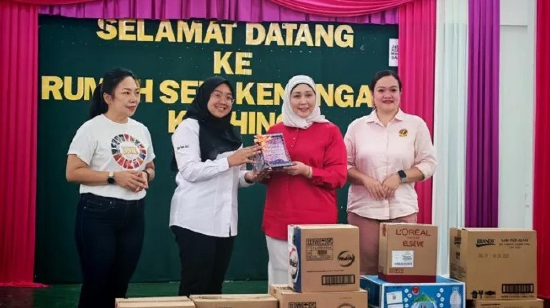 2026年2月10日，莎丽法哈西达（右2）在古晋12哩鲁玛斯里肯南，为砂青年团妇女组移交援助金仪式主持开幕后，接领纪念品。