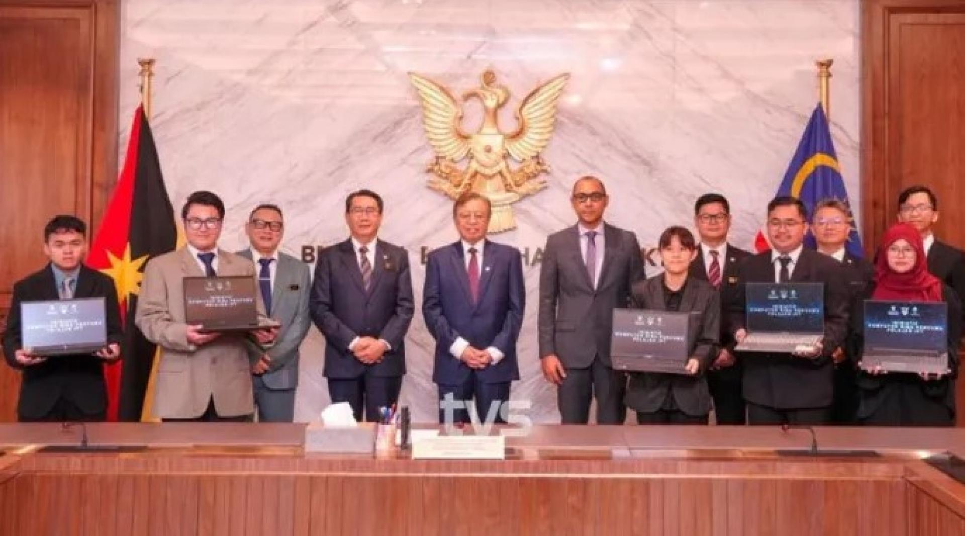 2026年2月11日，阿邦佐哈里（中）在Satria Pertiwi综合礼堂出席笔电象征性移交仪式后，与法兹鲁丁（左）及学生合影。