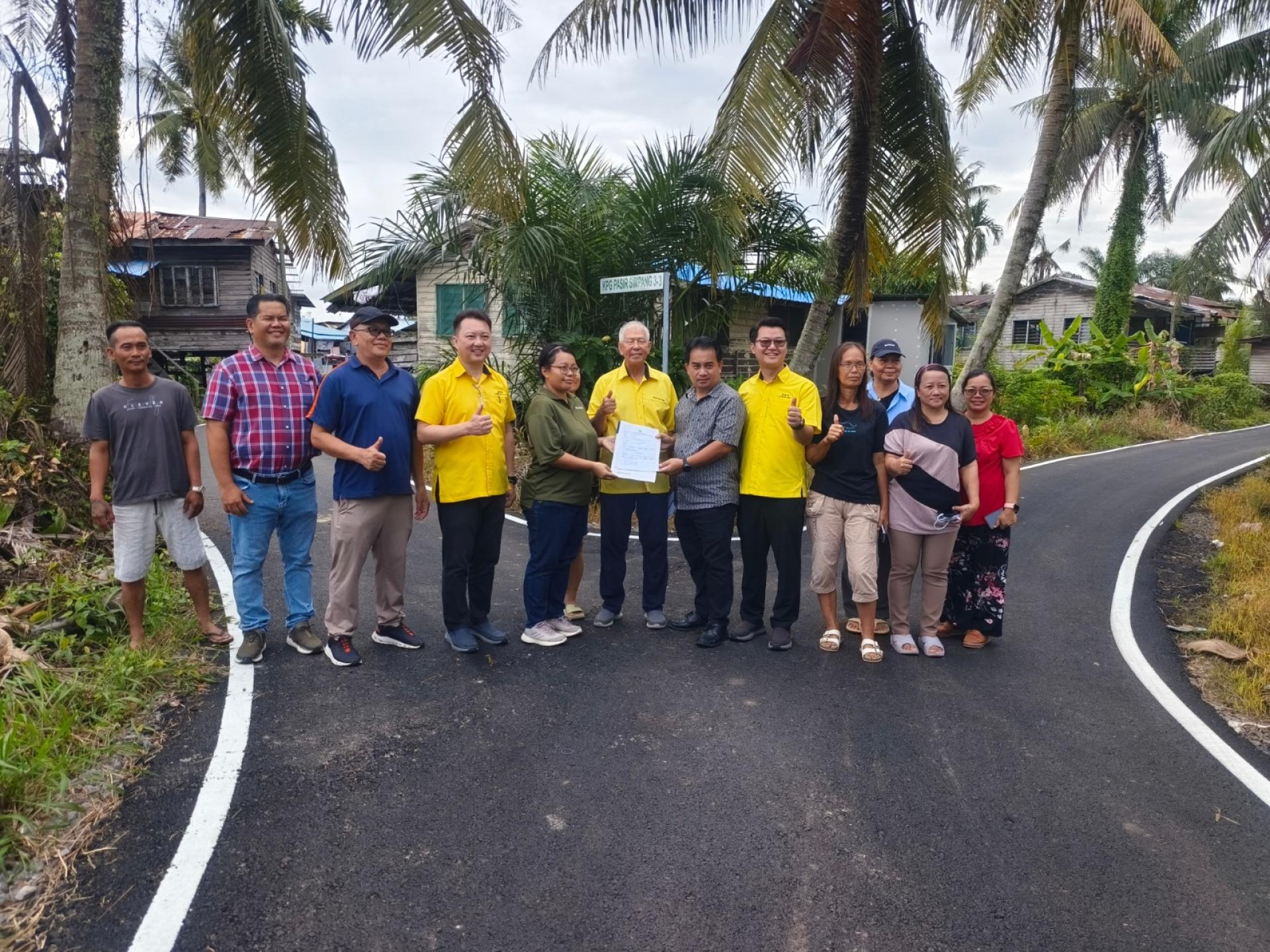 砂旅游部副部长拿督陈超耀（右7）见证承包商代表将竣工的沥青道路工程移交予美里市政局代表官员披得（右6）。