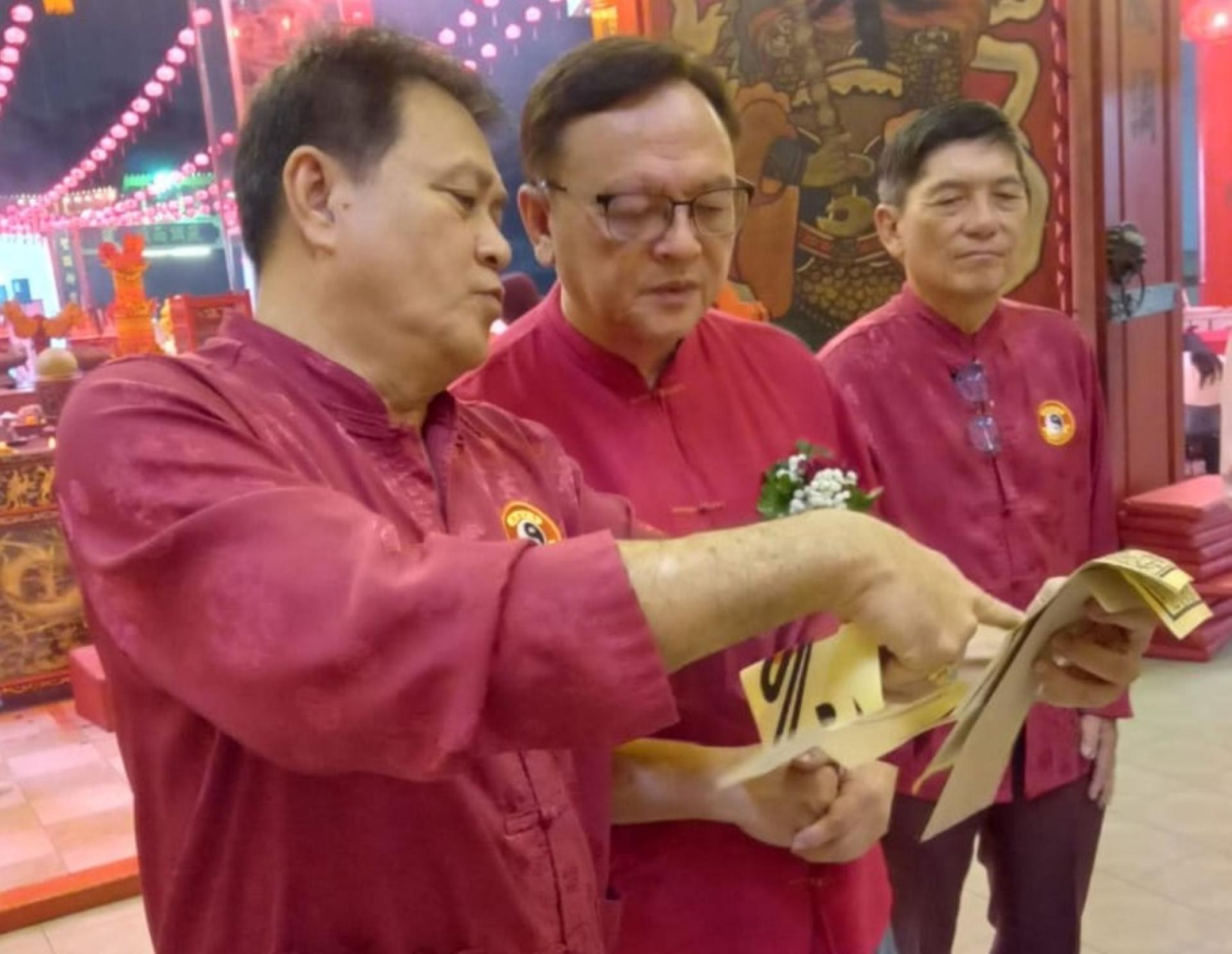 古晋东嶽观主席方文祥太平局绅（左）向拿督罗克强（中）介绍该观福品；右为方明生。