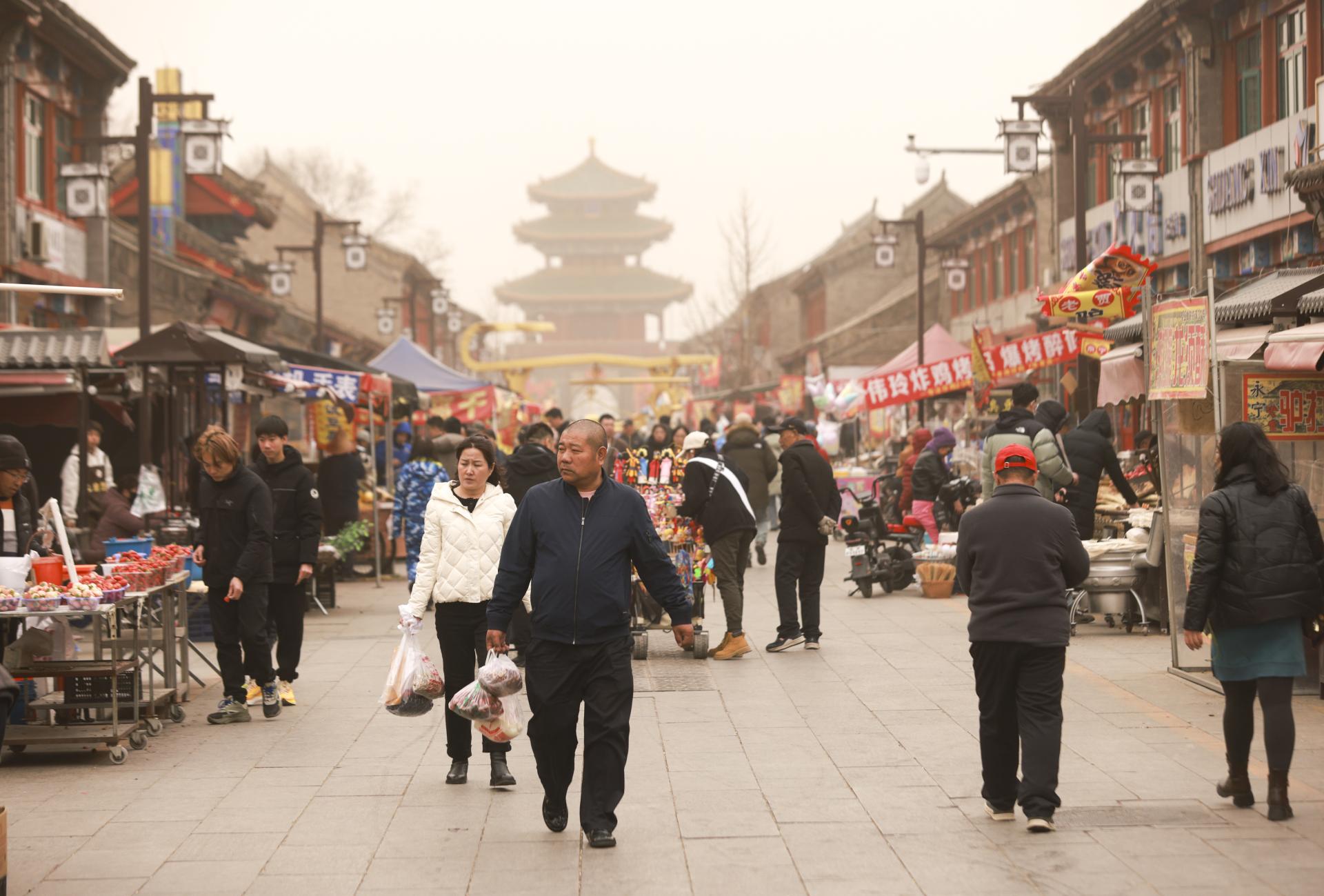 北京21日遭遇大风沙尘天气，图为市民在延庆永宁大集采购年货。