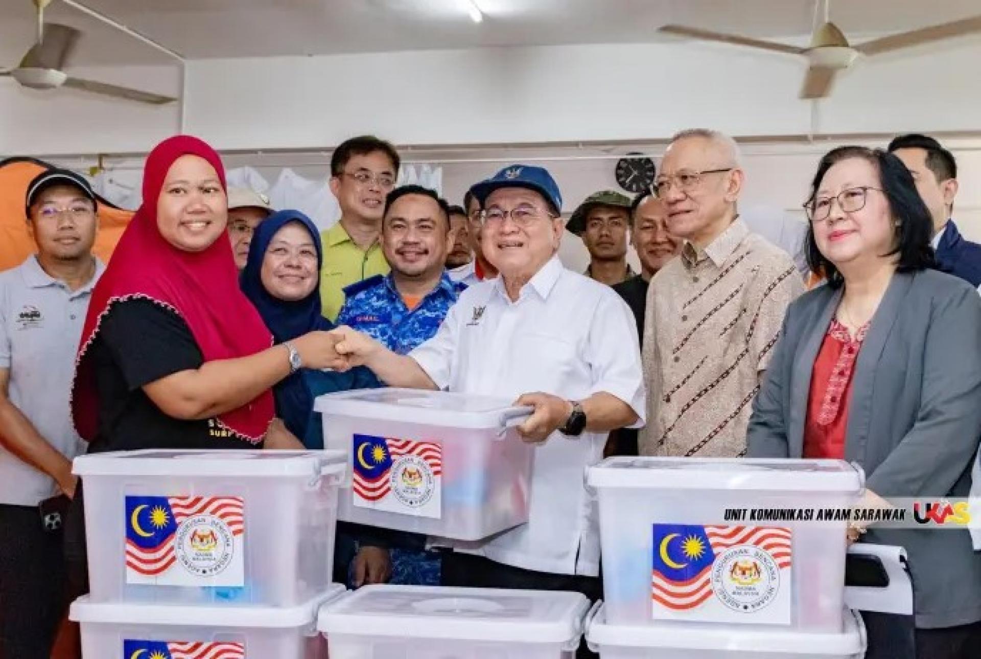 道格拉斯（中）在双溪茂岗村达鲁尔伊斯提克拉尔清真寺向一名洪水受灾者发放援助，依布拉欣（右2）及其他贵宾在旁观看，日期为2026年2月22日。