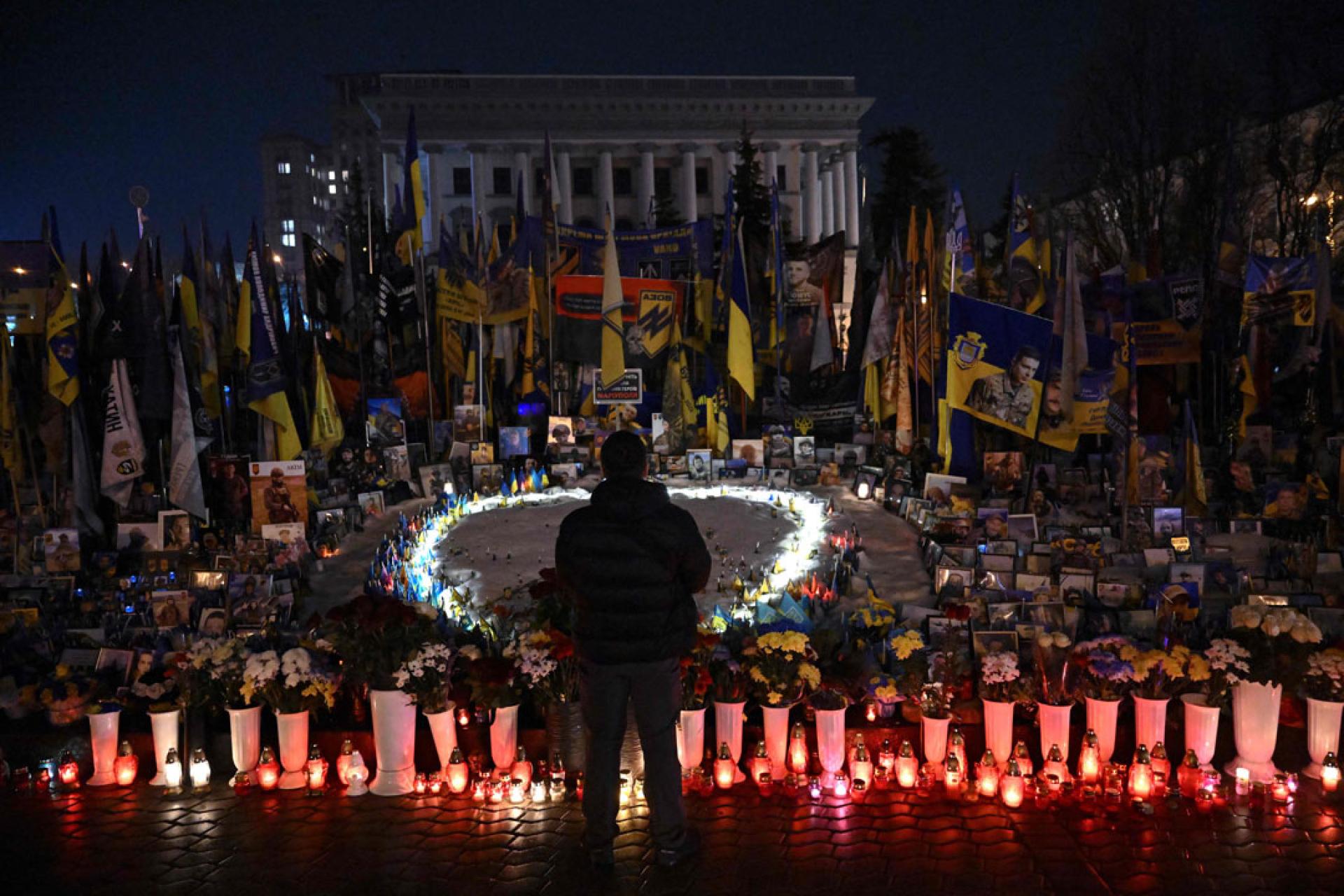 在俄乌战争4周年之际，一名男子站在基辅独立广场上为乌克兰和外国士兵搭建的临时纪念碑前。