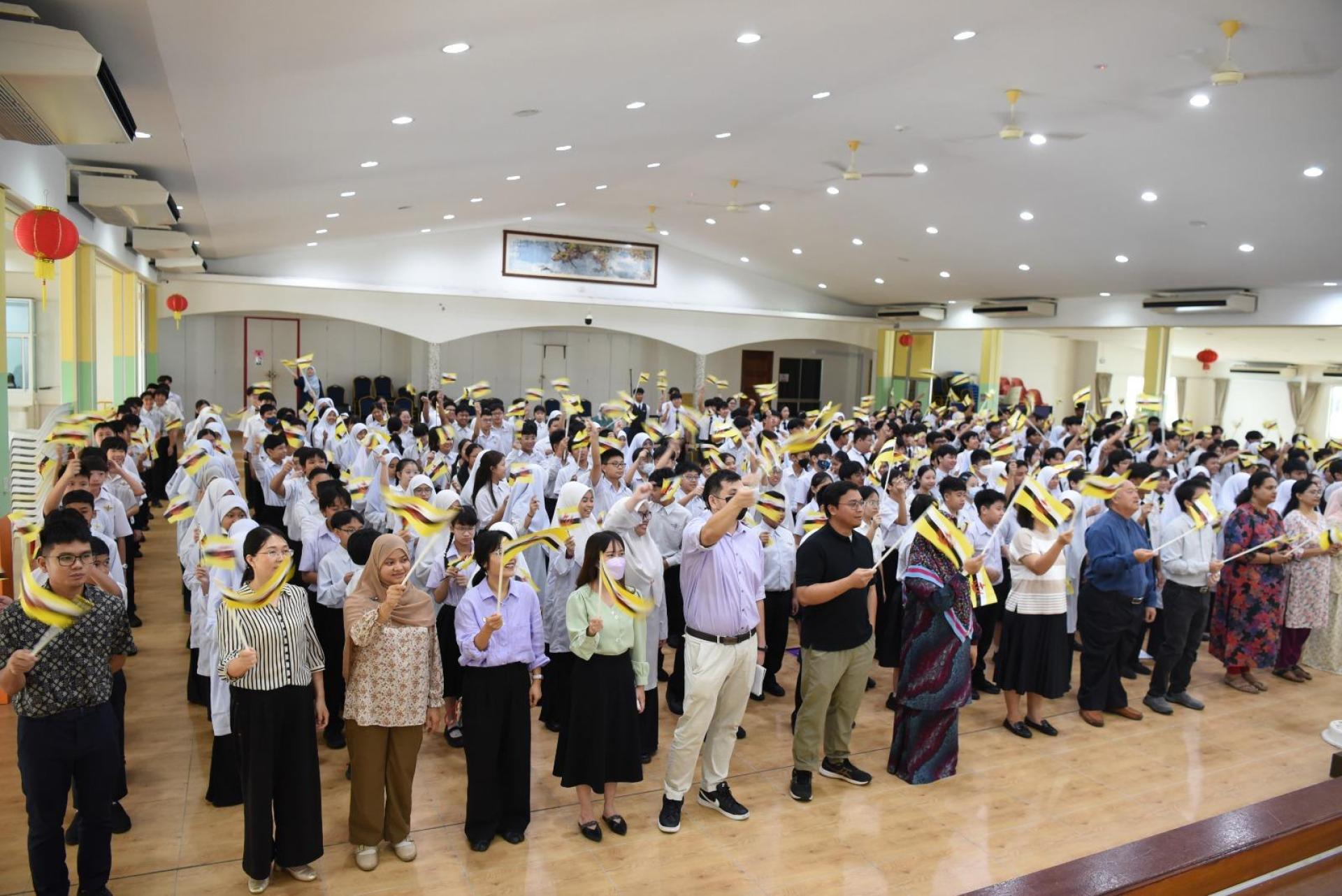 中学部的师生在高唱爱国歌曲时，共同挥舞起手中的汶莱国旗，融入到浓厚的爱国主义氛围中。