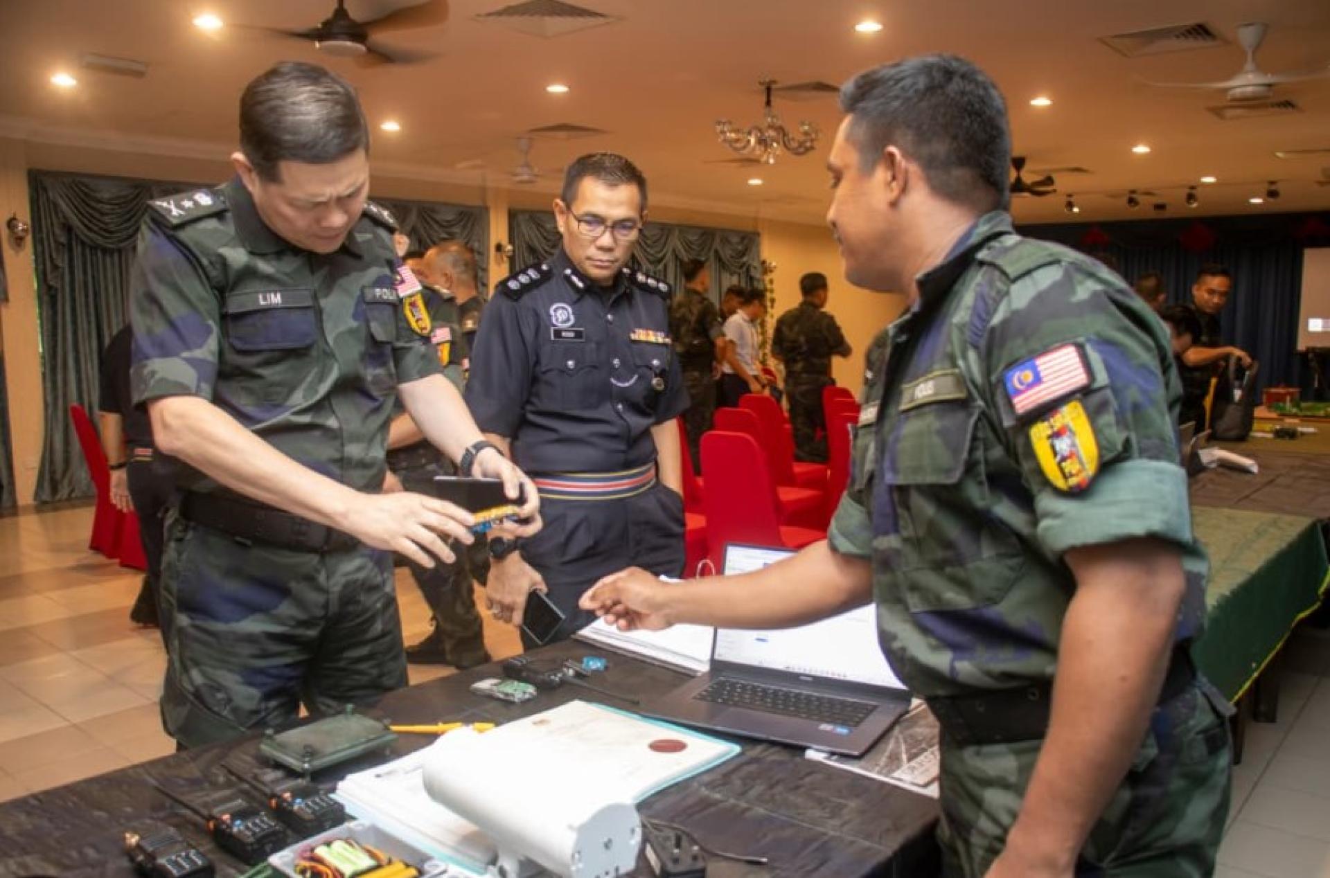 砂拉越总务行动部队旅指挥官林柏辉（左）在简报及示范中检查侦测传感器，副指挥官罗斯迪伊奈在旁观看。