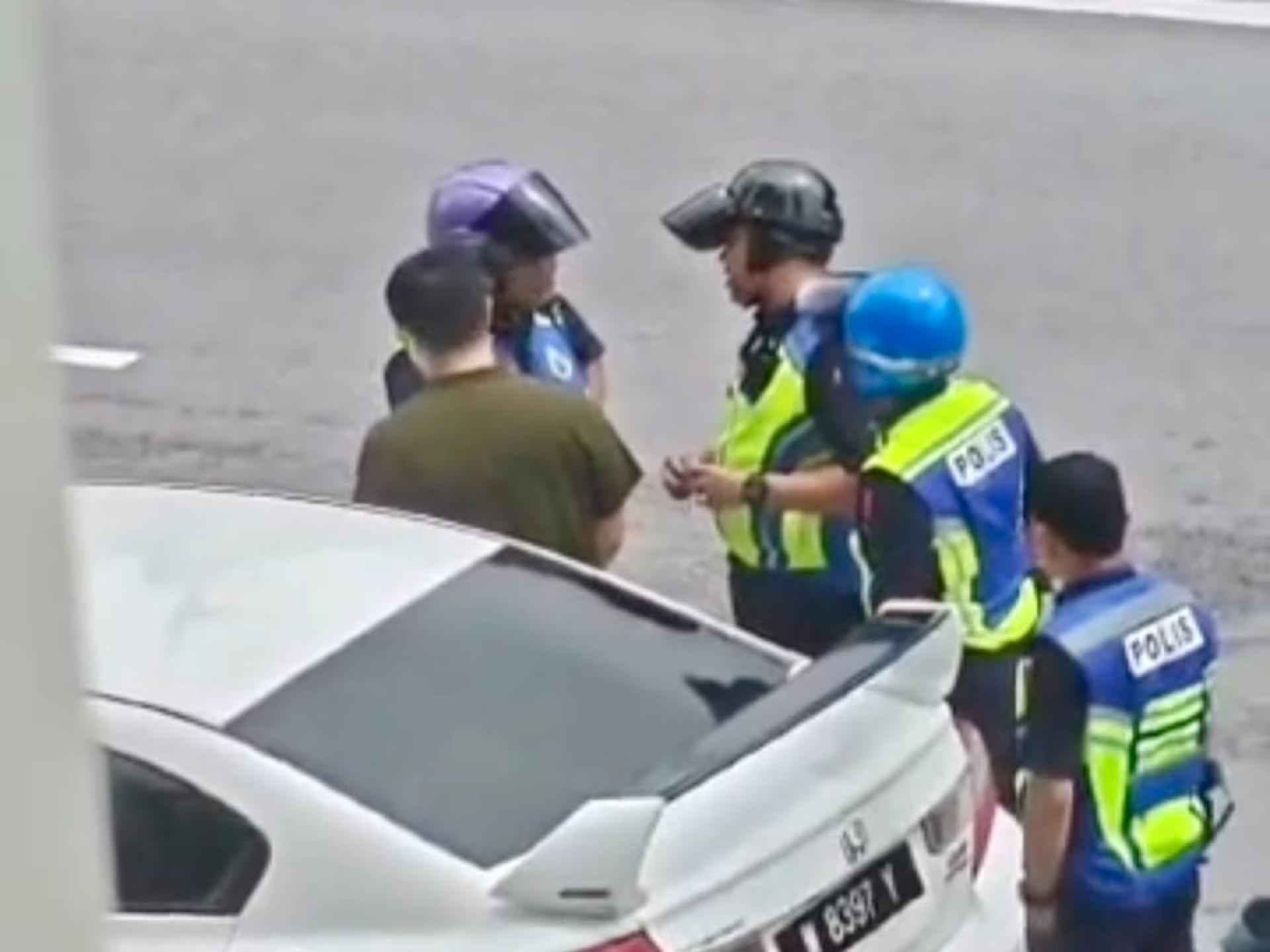 4名警察在路边围着一名驾驶者。