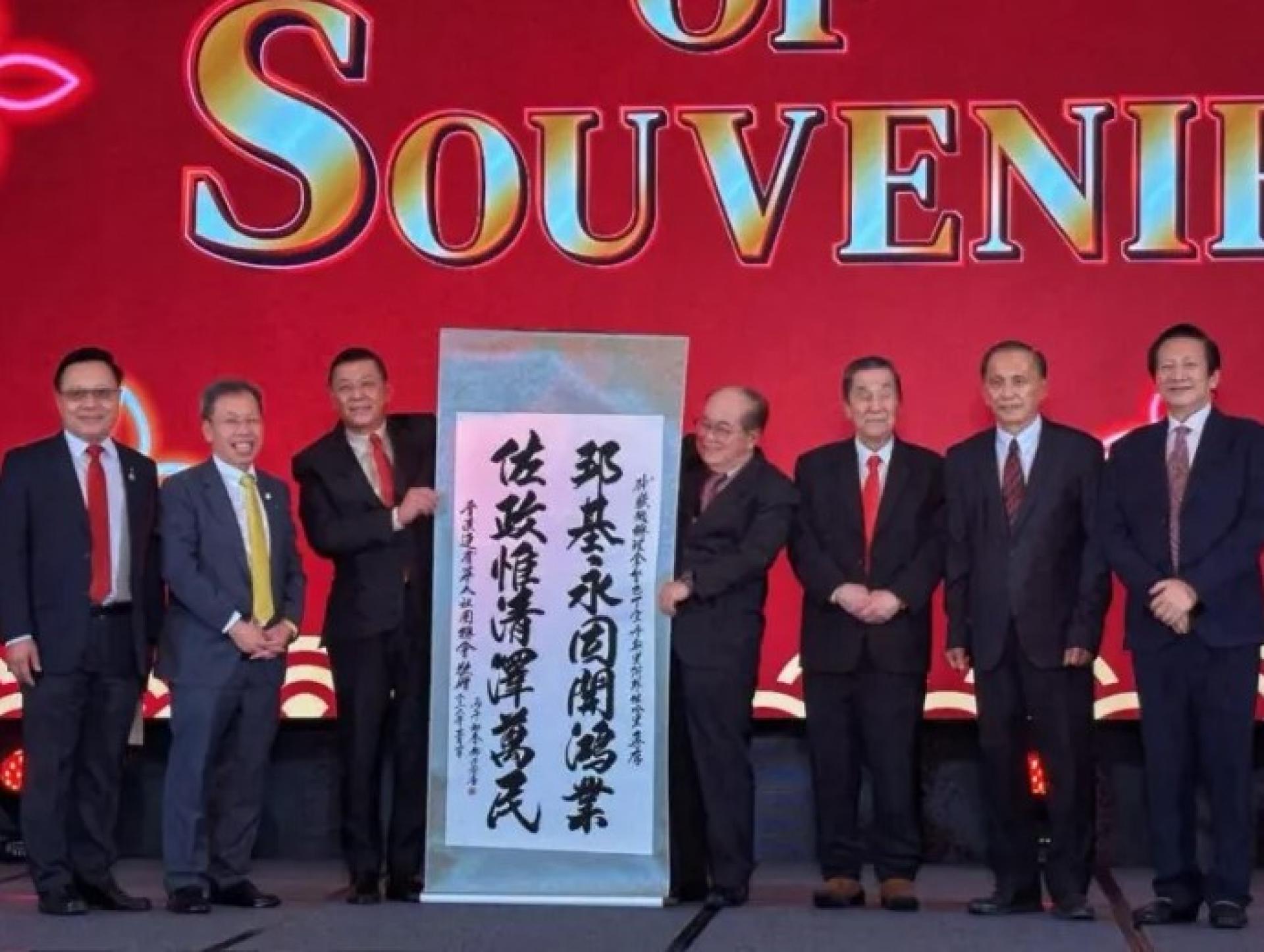 道格拉斯（右4）在3月1日活动中接过FCAKSS主席黄良杰（左3）赠送的书法作品作为纪念。