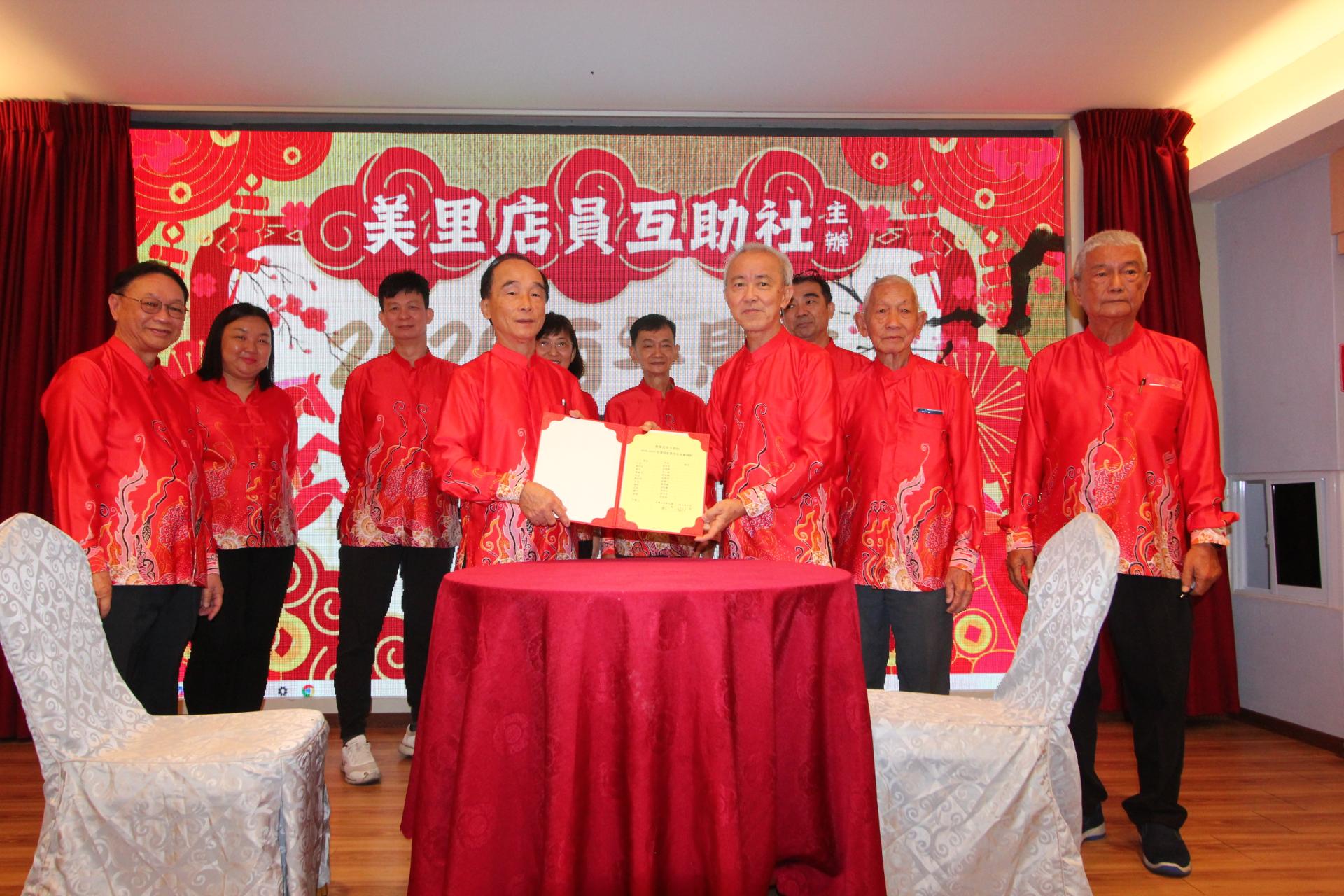 美里店员互助社社长张火生（左）从宋志富手中接过宣誓书。