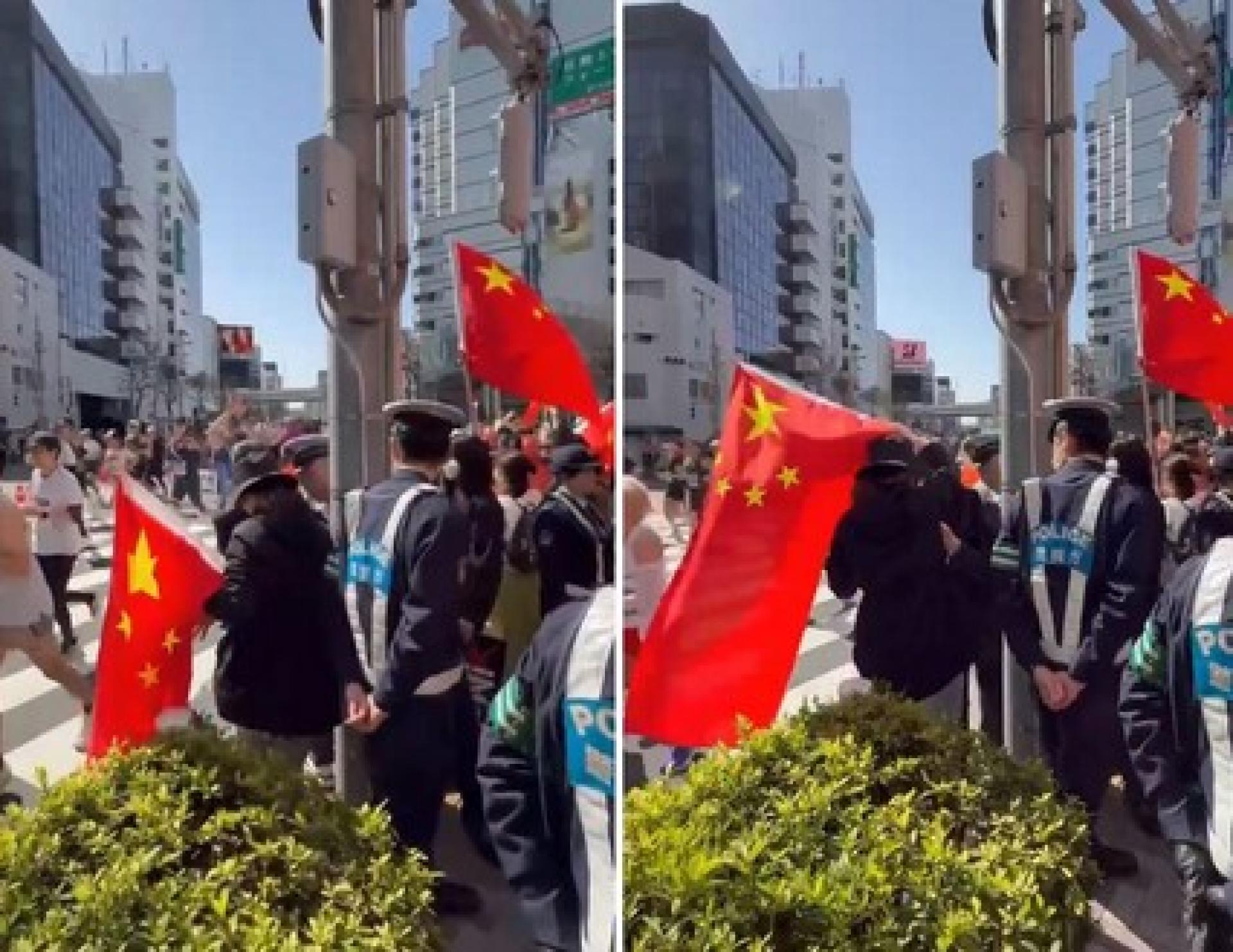 马拉松赛道旁，出现高举巨幅中国五星旗的民众，掀起批评声浪。