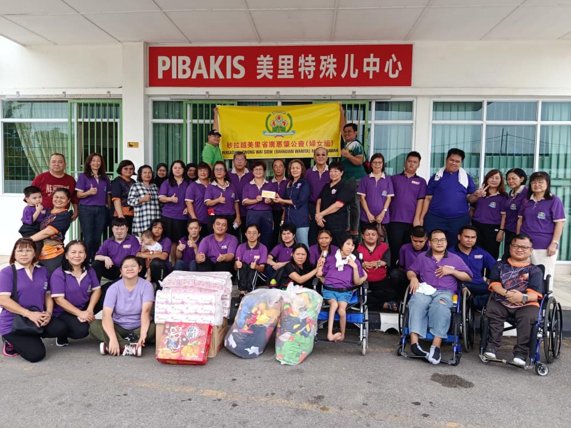 美里省广惠肇公会妇女组筹备会主席陈双风（左11）移交新年红橘及生活用品予美里特殊儿中心秘书吴丽蓉女士（左13）代表接领；左9为妇女组主任陈彩虹，左10为评议员梁绍钧，左12为暑理会长张火生，左14为会长黄运祥。