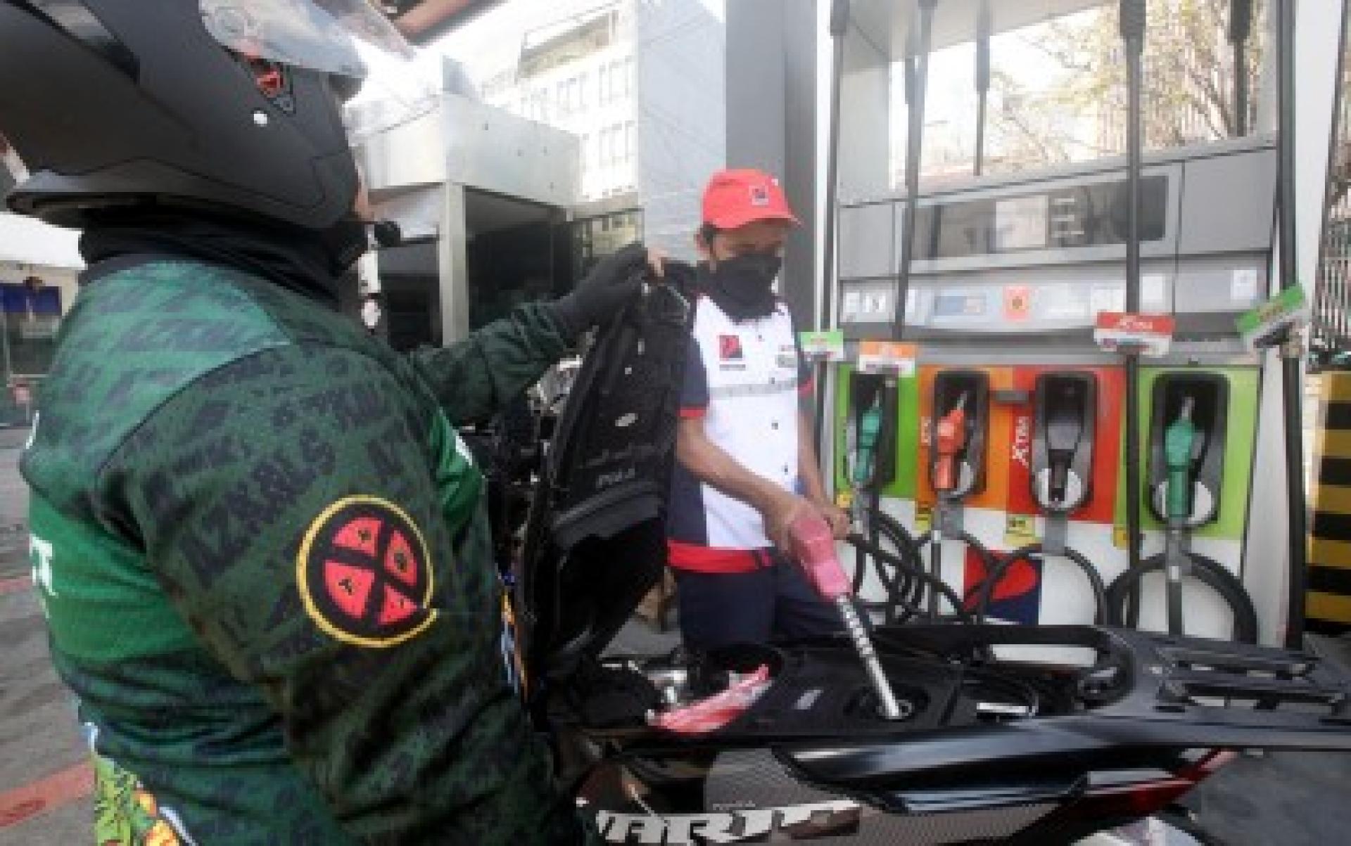 2月2日，在马尼拉帕科区的一个加油站，一名服务员正在给摩托车骑手加油。