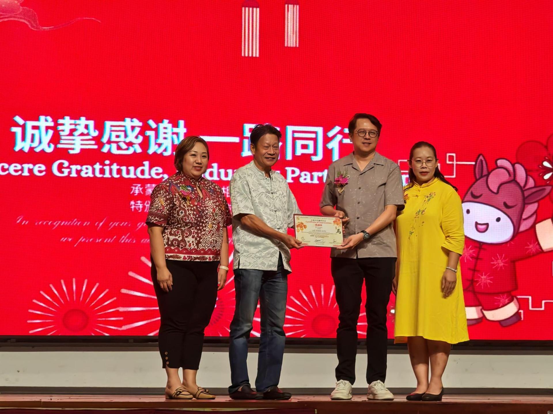 筹委会主席古晋市童军助理总监赖思伲（右2）赠送纪念品予主宾拿督蔡文铎（左2）。左1为古晋市童军总监廖美珠，右1为古晋市童军协会主席黄廉欢。