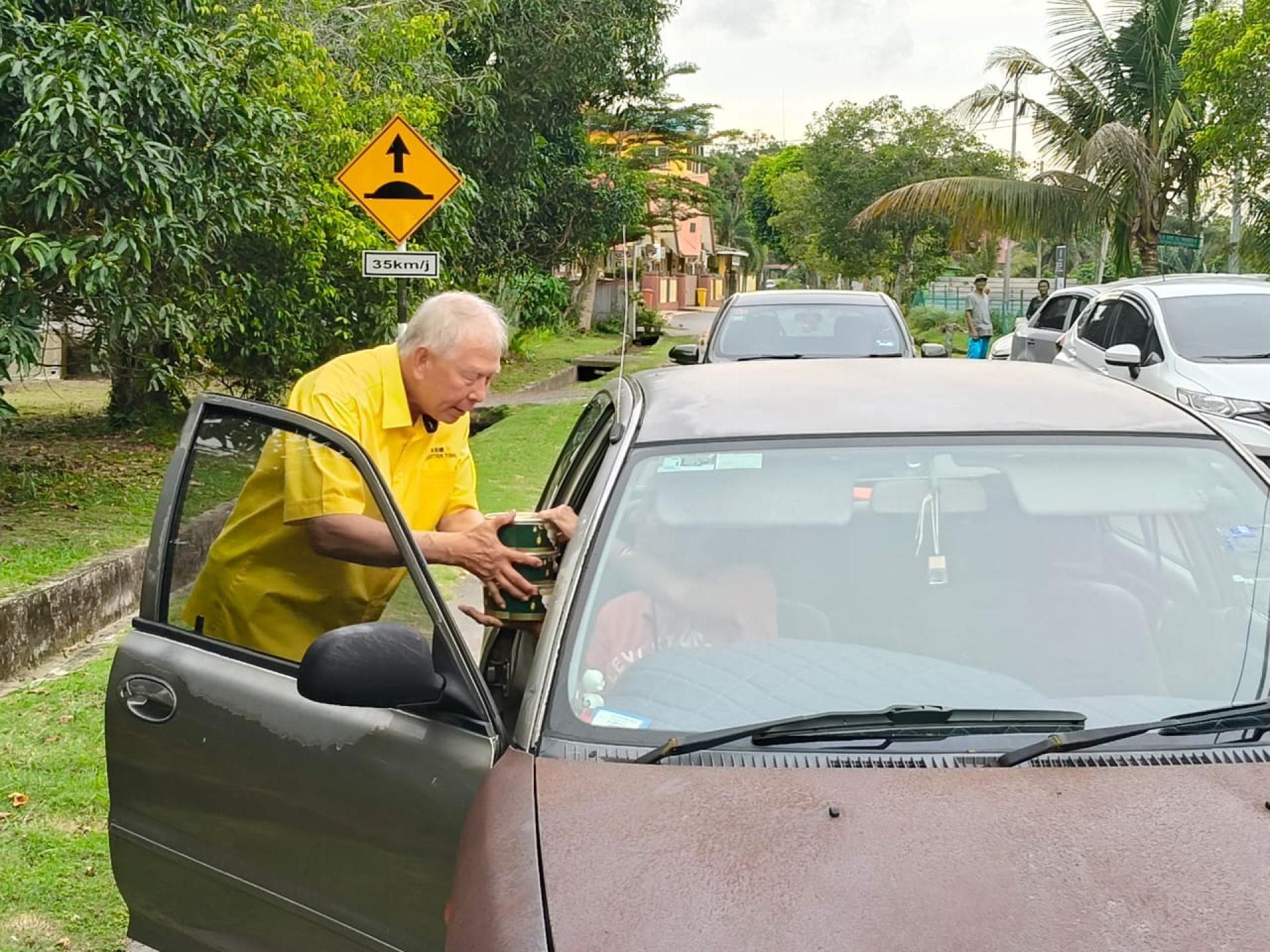 拿督陈超耀（左）派送杂锦粥予路过民众。