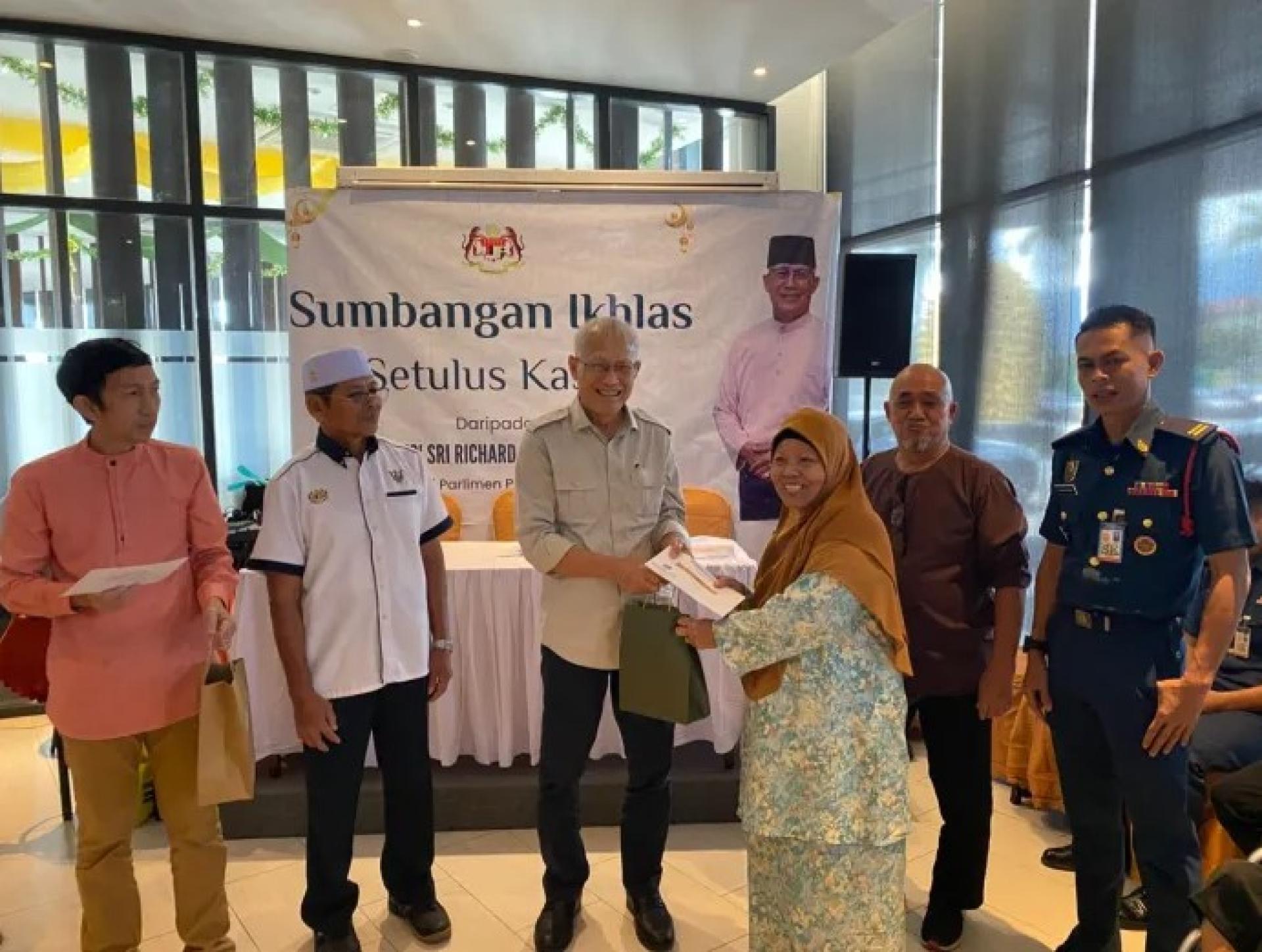 里奥特（左3）于2026年3月12日在西连Roxy Hotel活动上，向受助者移交现金援助及曲奇礼品。