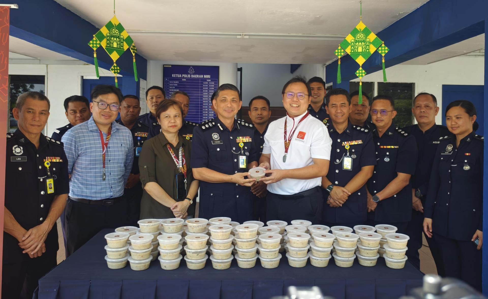 配合斋戒月的到来，美砂集团向美里警察总部派发100份杂锦粥合影。图4为美里警区主任李炳强助理总监从砂集团项目经理江师聪手中接过杂锦粥。