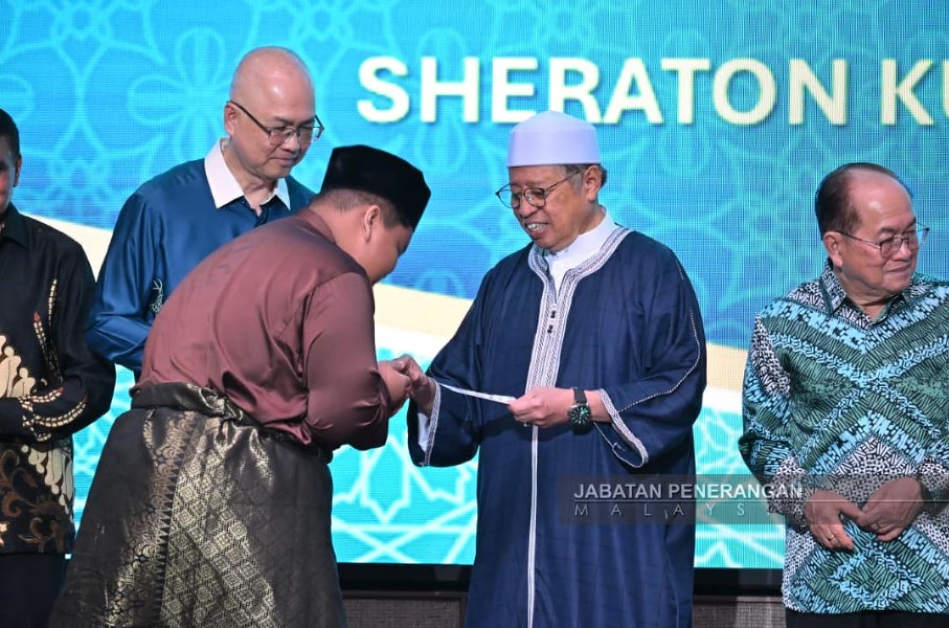 阿邦佐哈里（右2）在开斋活动中，将“duit Raya”赠与孤儿。 图：马来西亚新闻局。