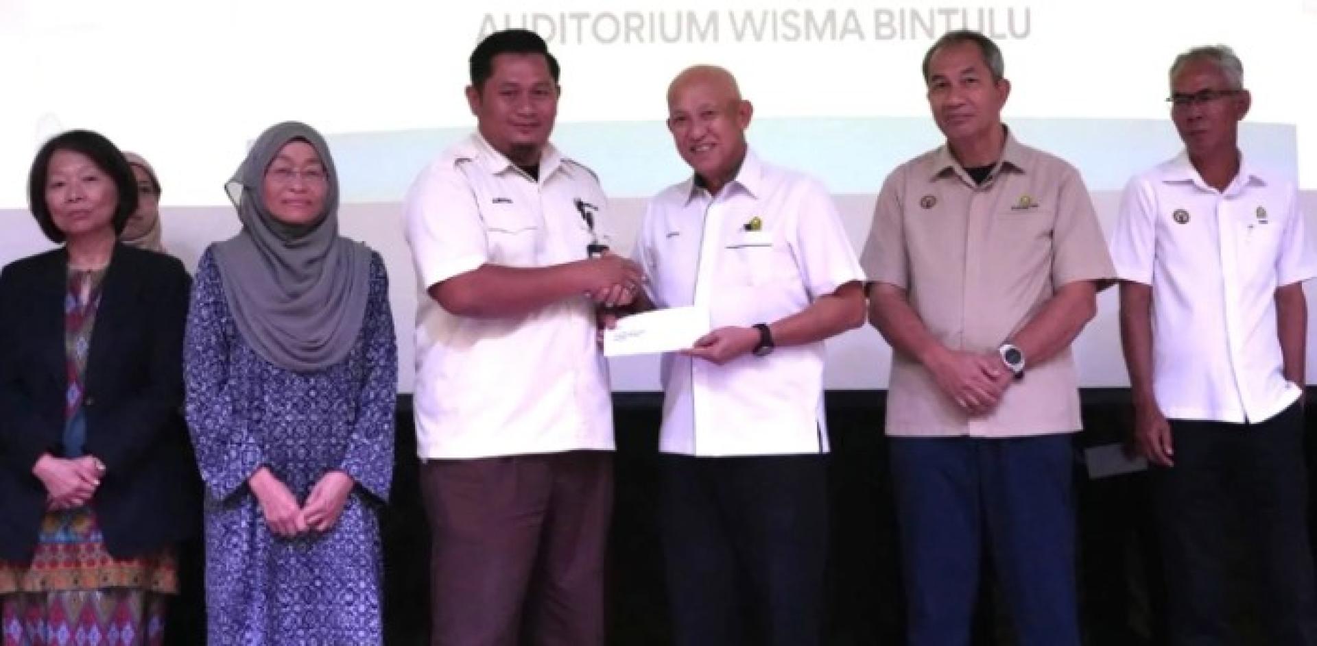 阿都拉希姆向民都鲁发展局的一名员工发放捐赠。