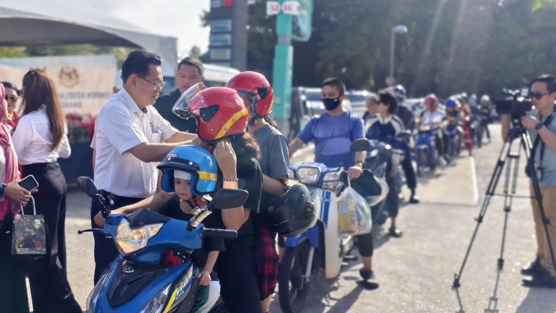 李景胜派发道路安全运动的宣传品及礼物予摩托骑士，并为摩托车骑士更换新安全头盔。